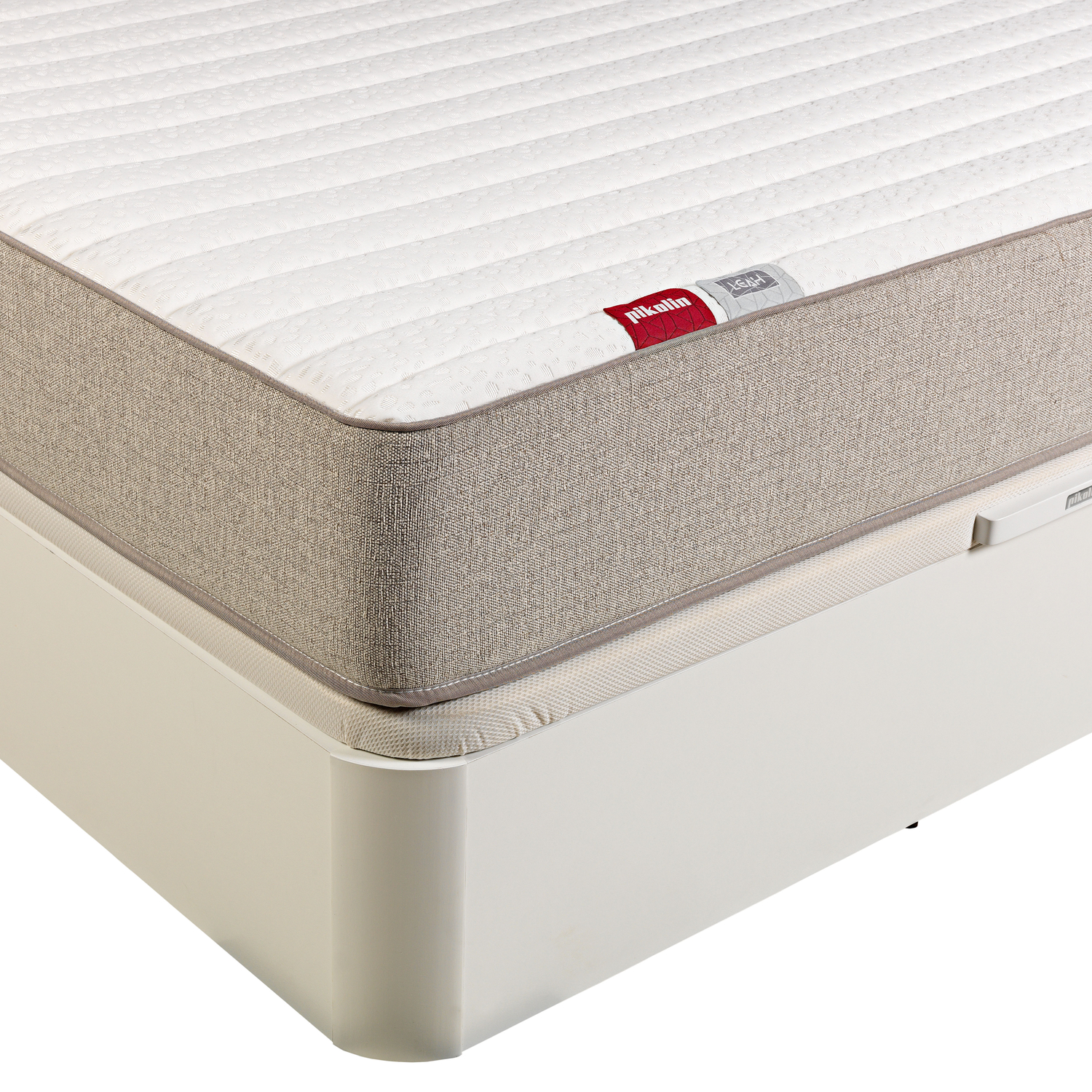 Un colchón blanco con borde beige sobre un somier blanco. Se ve una etiqueta que dice 'Pikolin'.