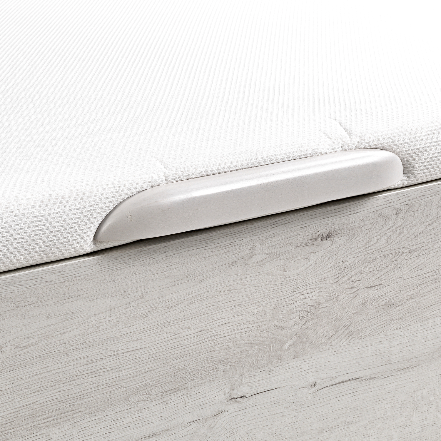 Colchón blanco sin costuras con asa plateada sobre muebles de madera.