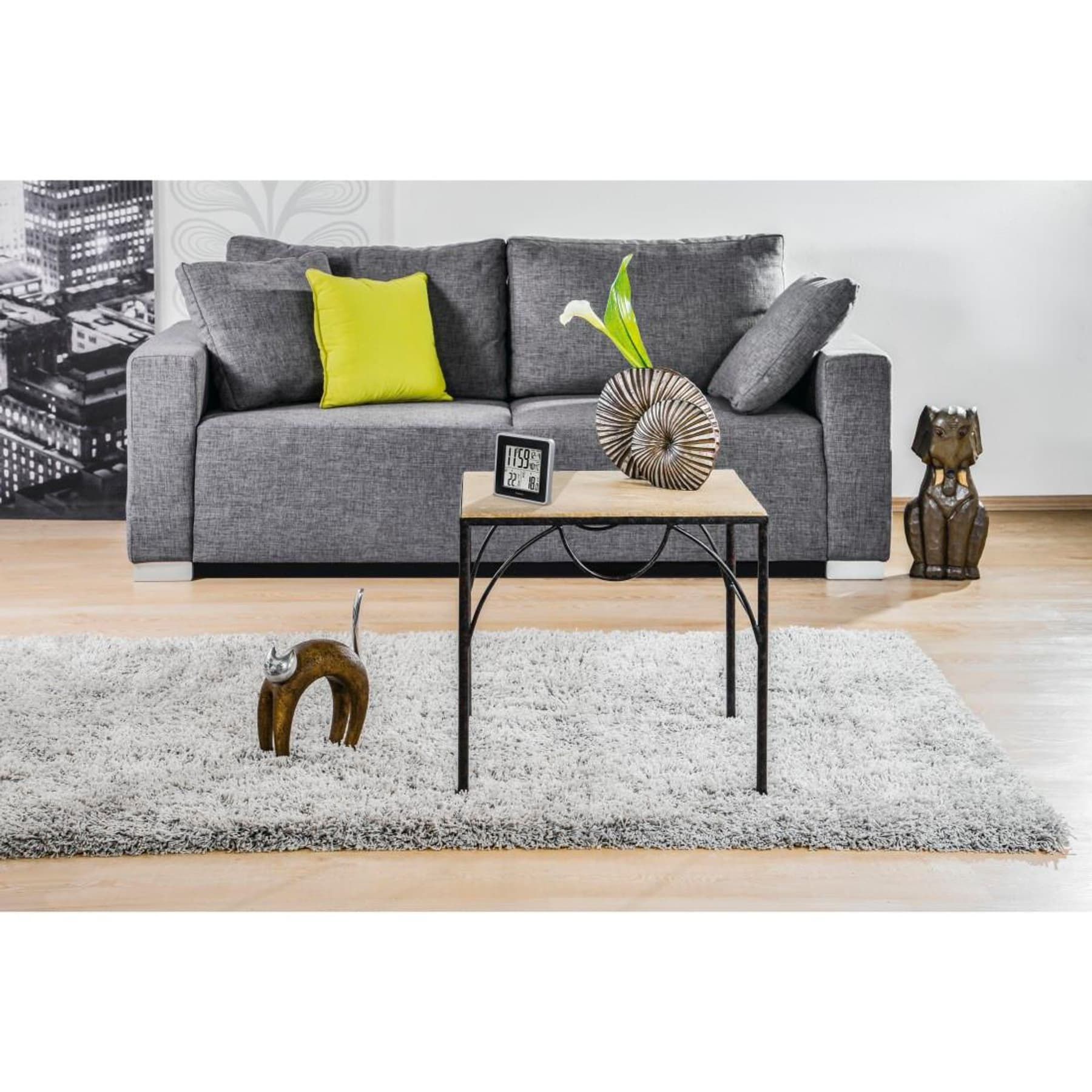 Grijze bank met kussens, klein tafeltje, kleed en decoraties.