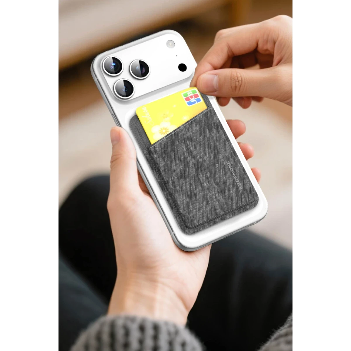 Beyaz iPhone'da gri kumaş kartlık, eller tarafından tutuluyor.