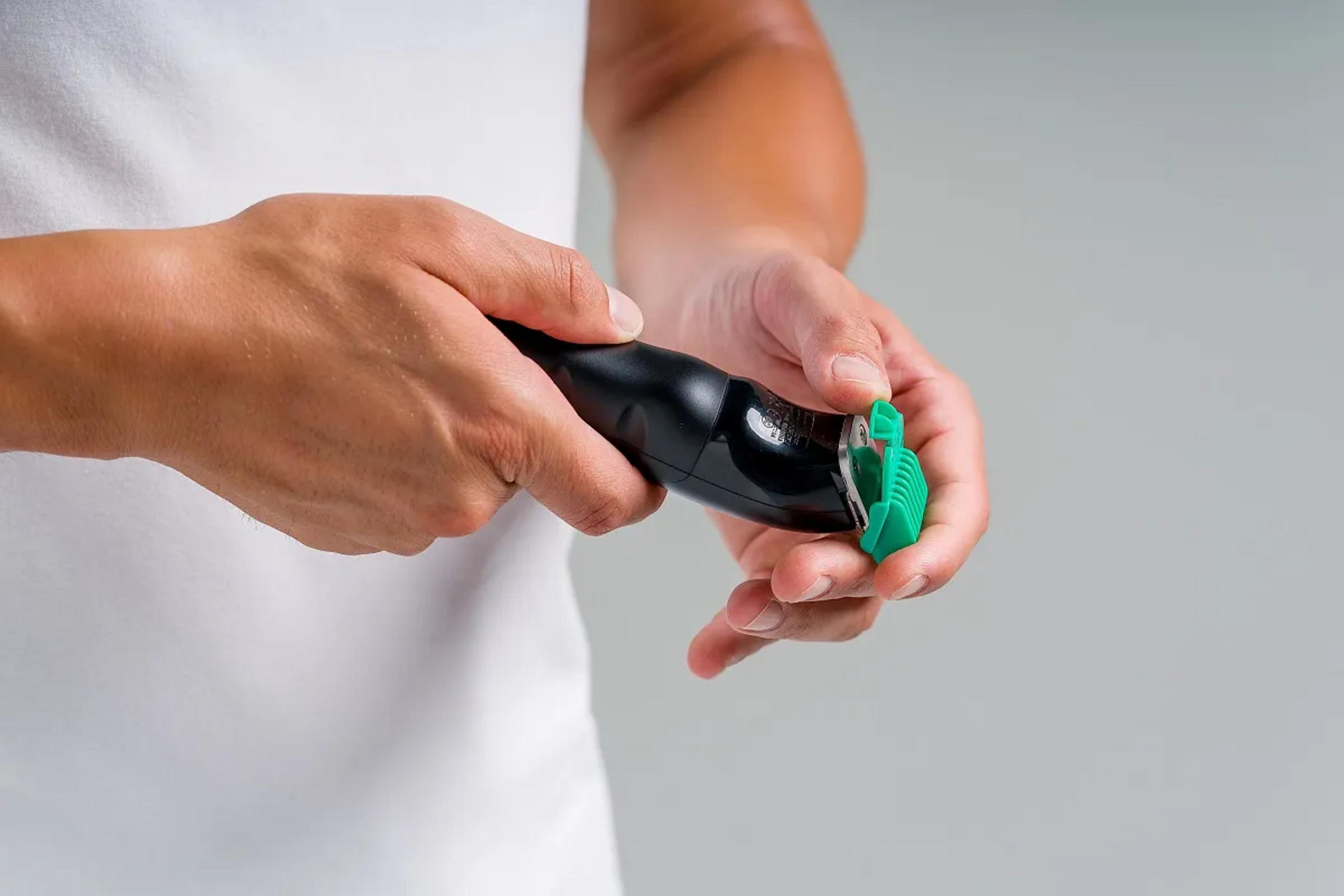 Osoba trzyma czarny trymer z zieloną nasadką.