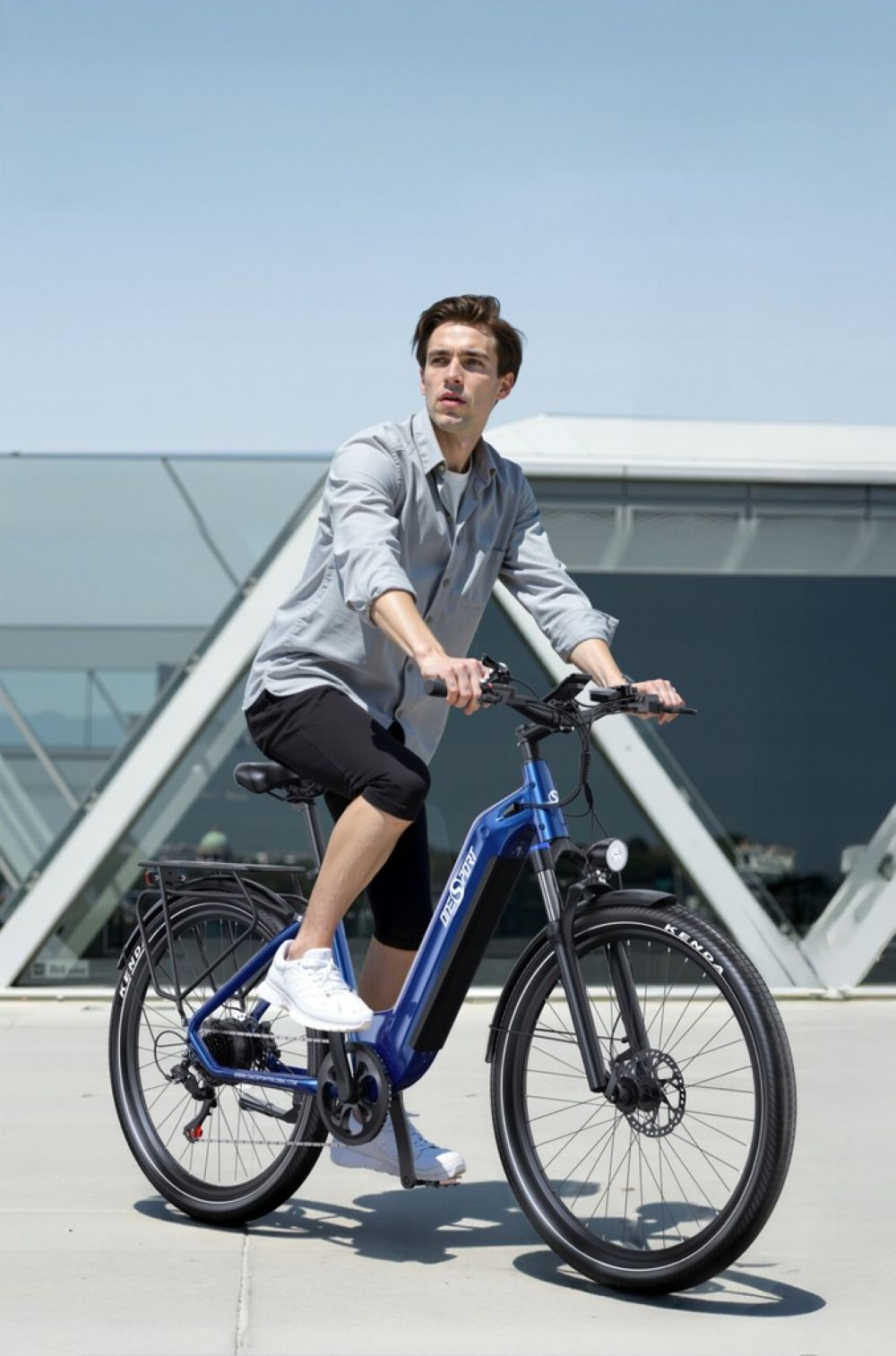 Un hombre monta una bicicleta eléctrica azul frente a arquitectura moderna.