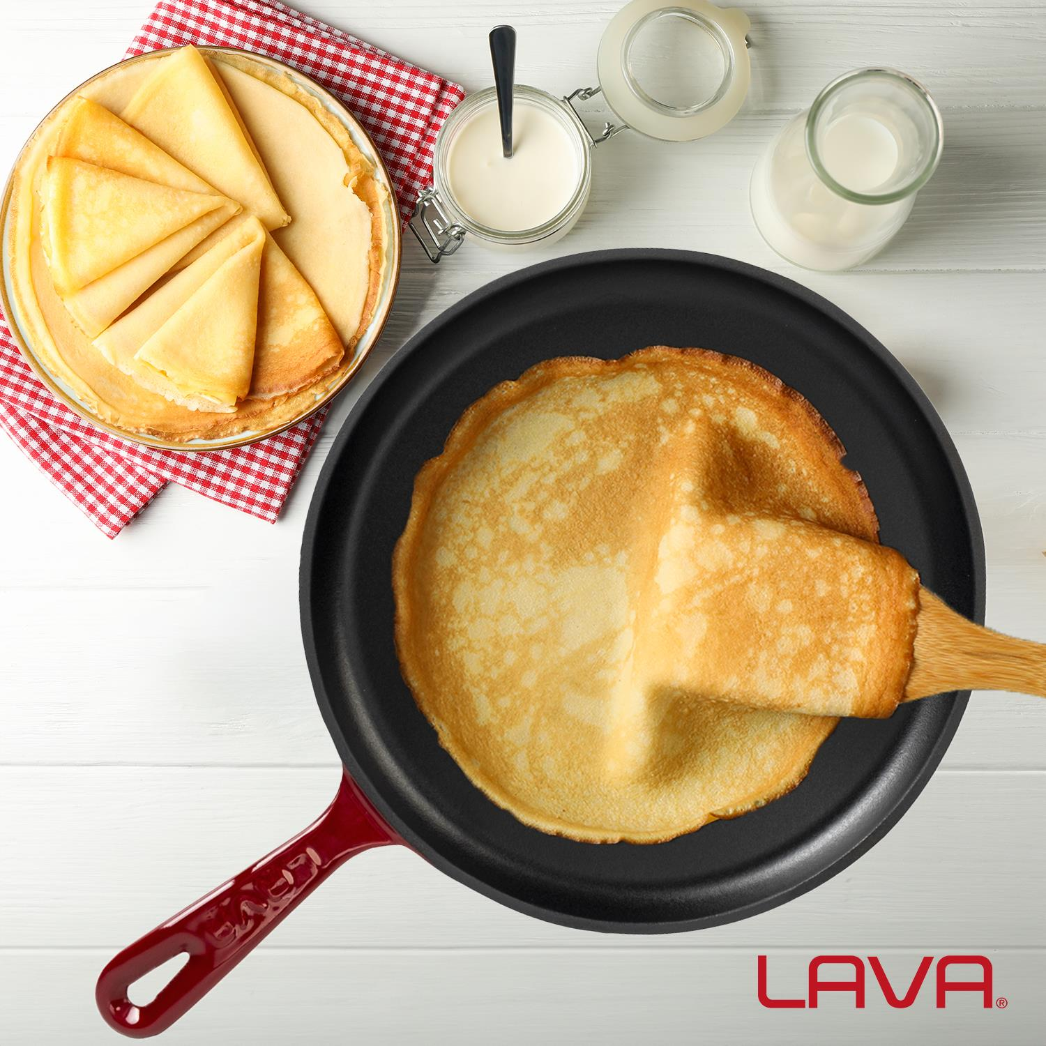 Kırmızı tavada tahta spatula ile bir krep çevriliyor. Katlanmış krepler yakınlarda duruyor.