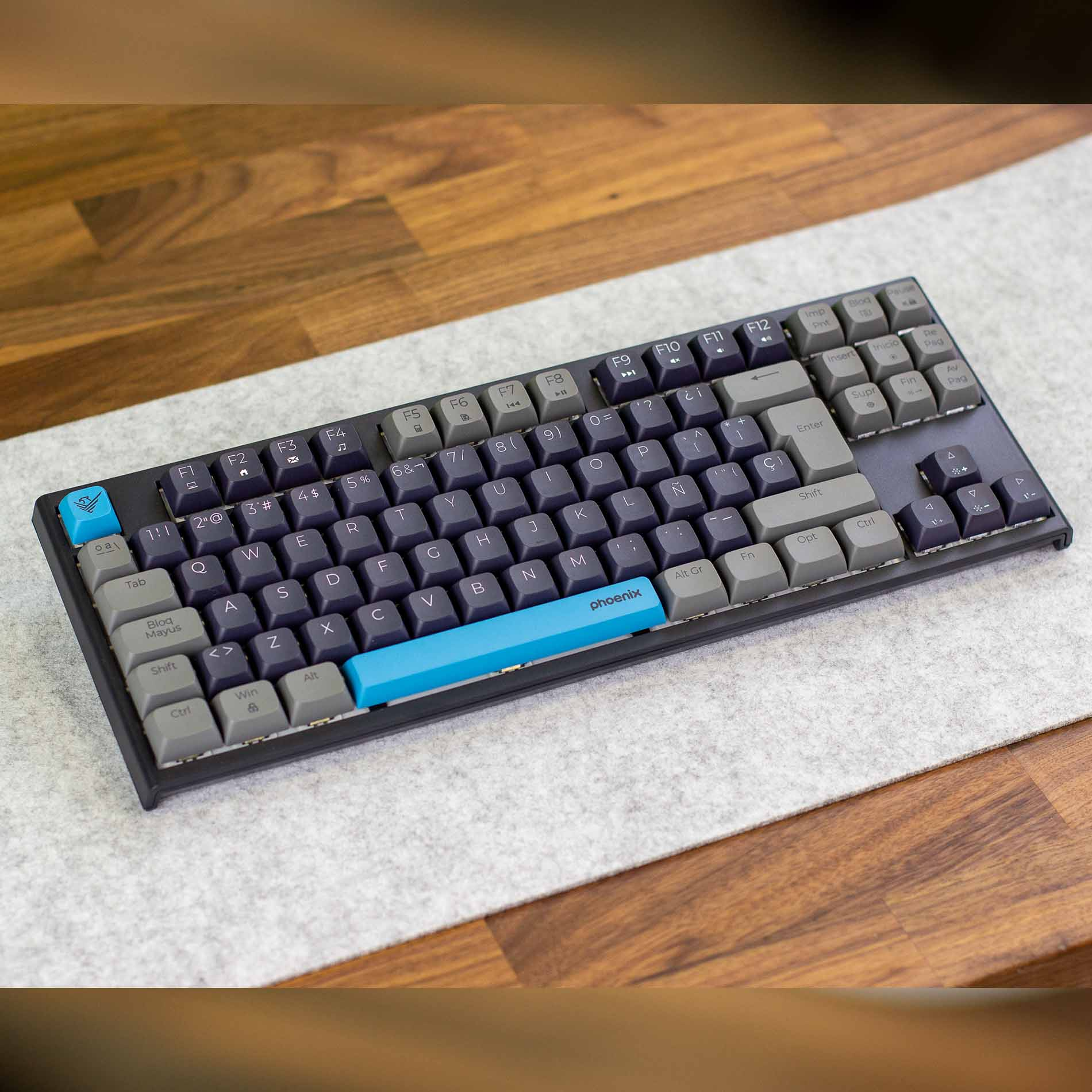 Un teclado negro con teclas gris oscuro y gris claro sobre un fondo de madera.