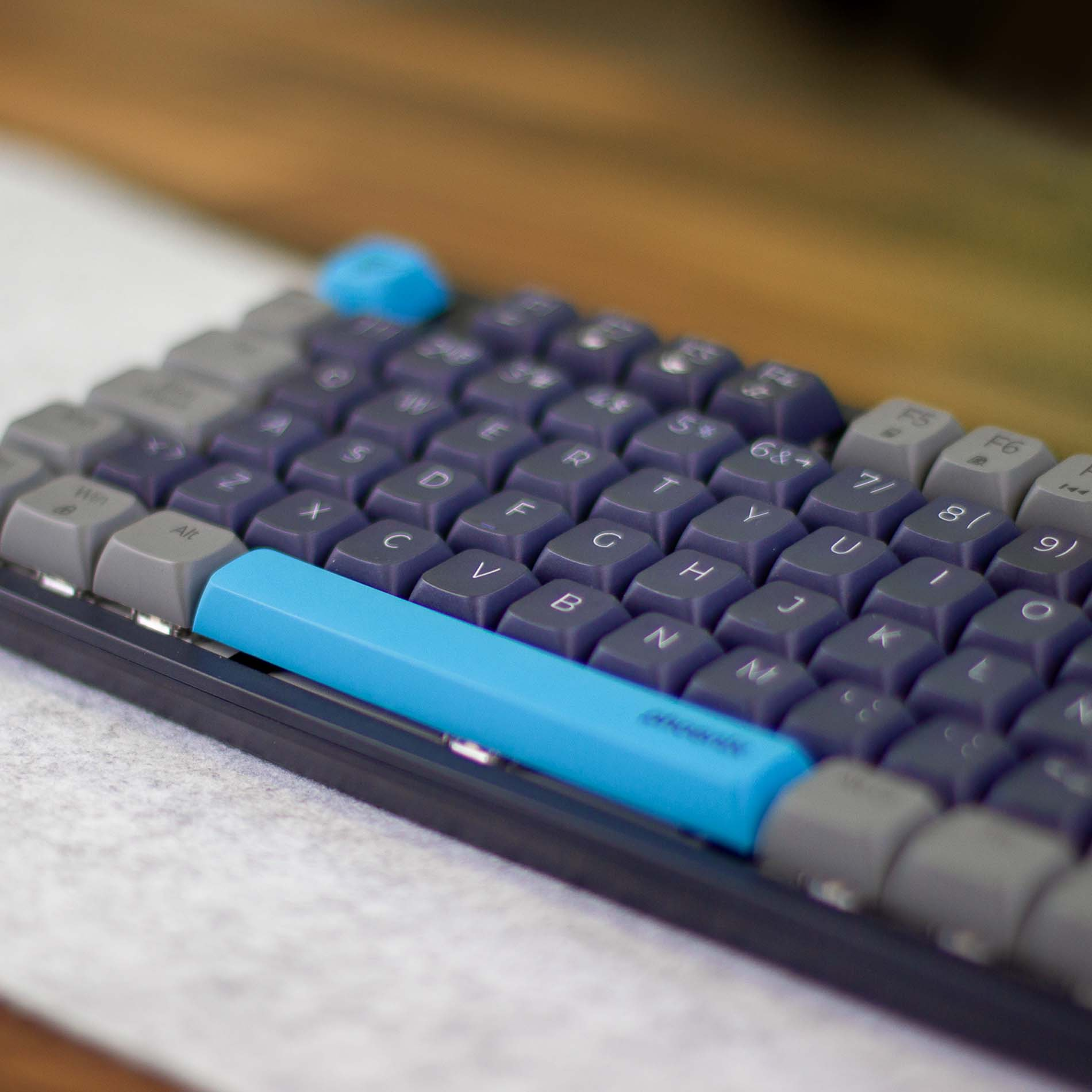 Un primer plano de un teclado con teclas azules y grises sobre una mesa de madera.
