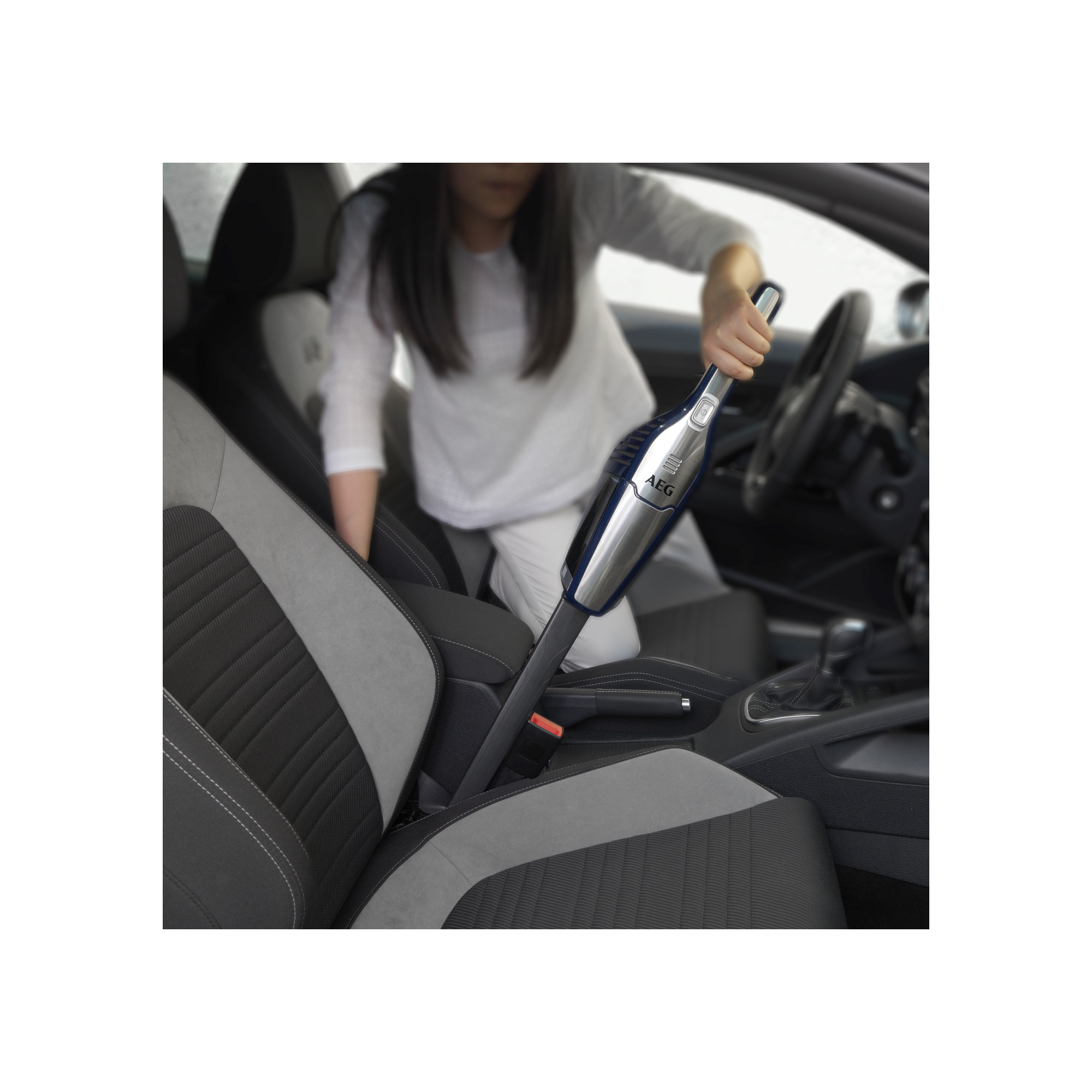 Osoba odkurza wnętrze samochodu odkurzaczem ręcznym.
