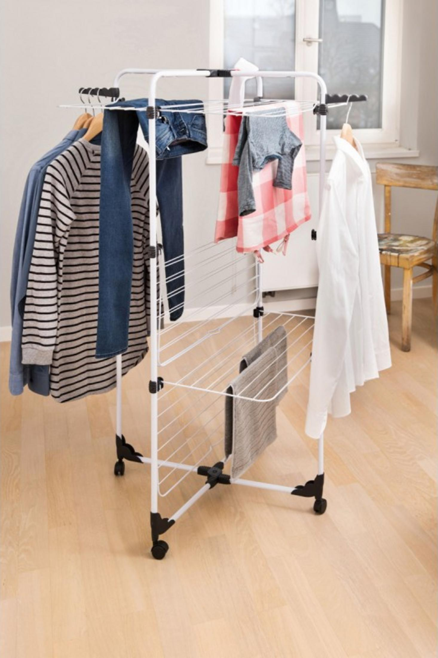Ein weißer Wäscheständer mit Kleidung und Handtüchern im Zimmer.