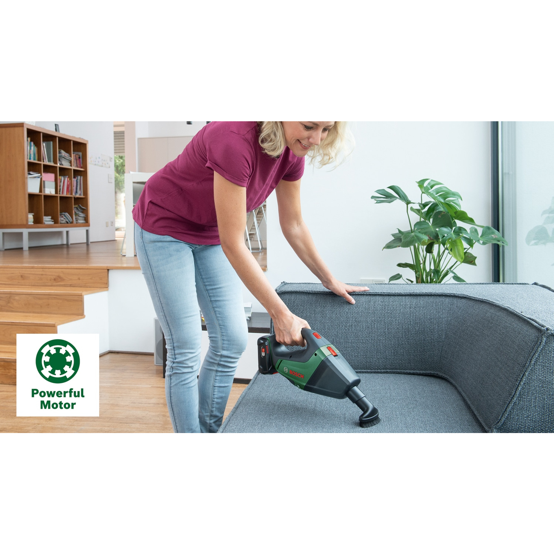 Kadın kablosuz el süpürgesiyle koltuk süpürüyor. Bosch logosu.