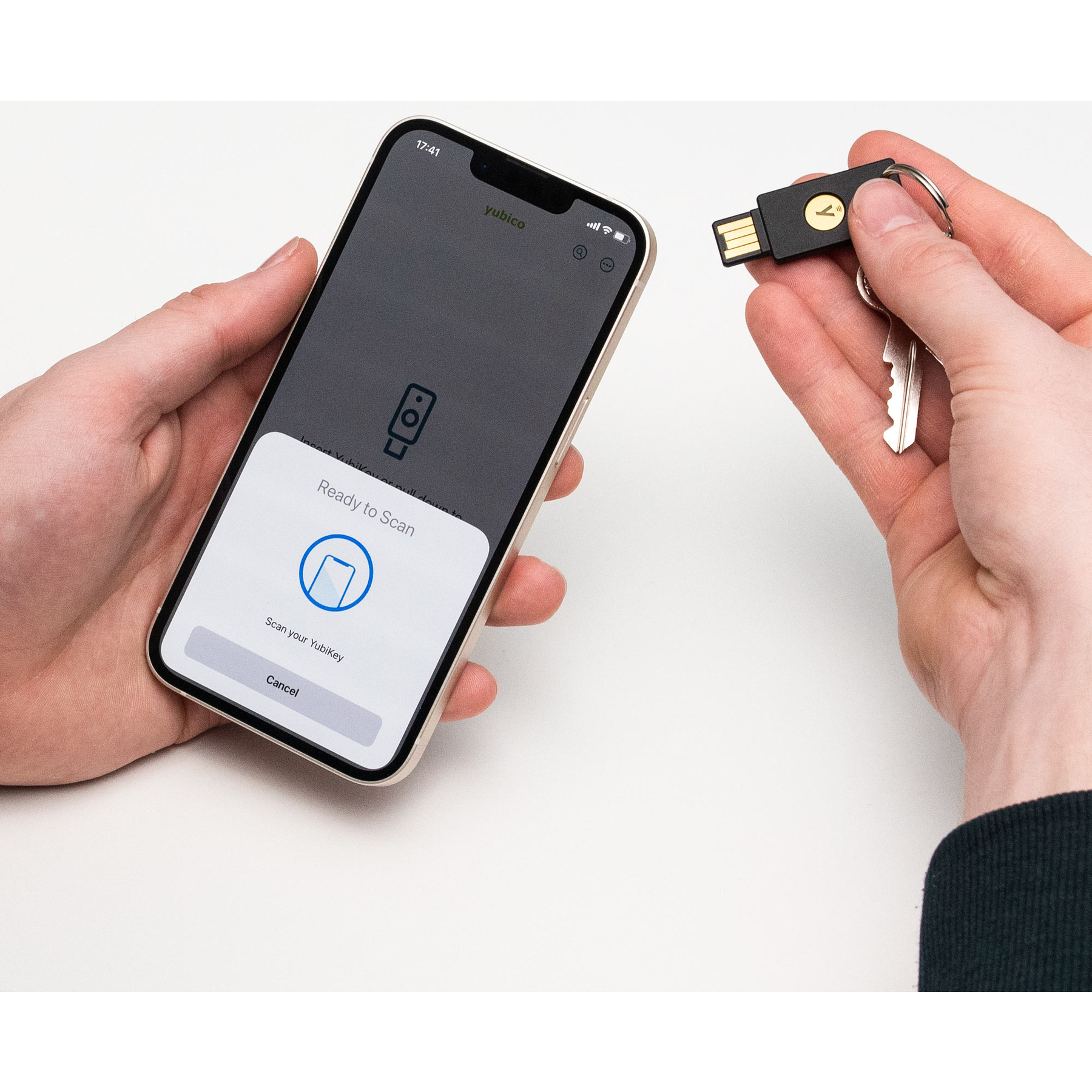Eine Hand hält ein Smartphone, eine andere hält einen YubiKey mit Schlüsseln.