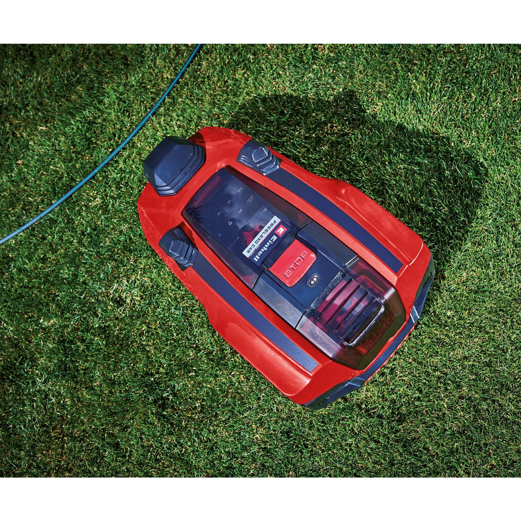 Czerwony robot koszący na zielonej trawie z niebieskim kablem.