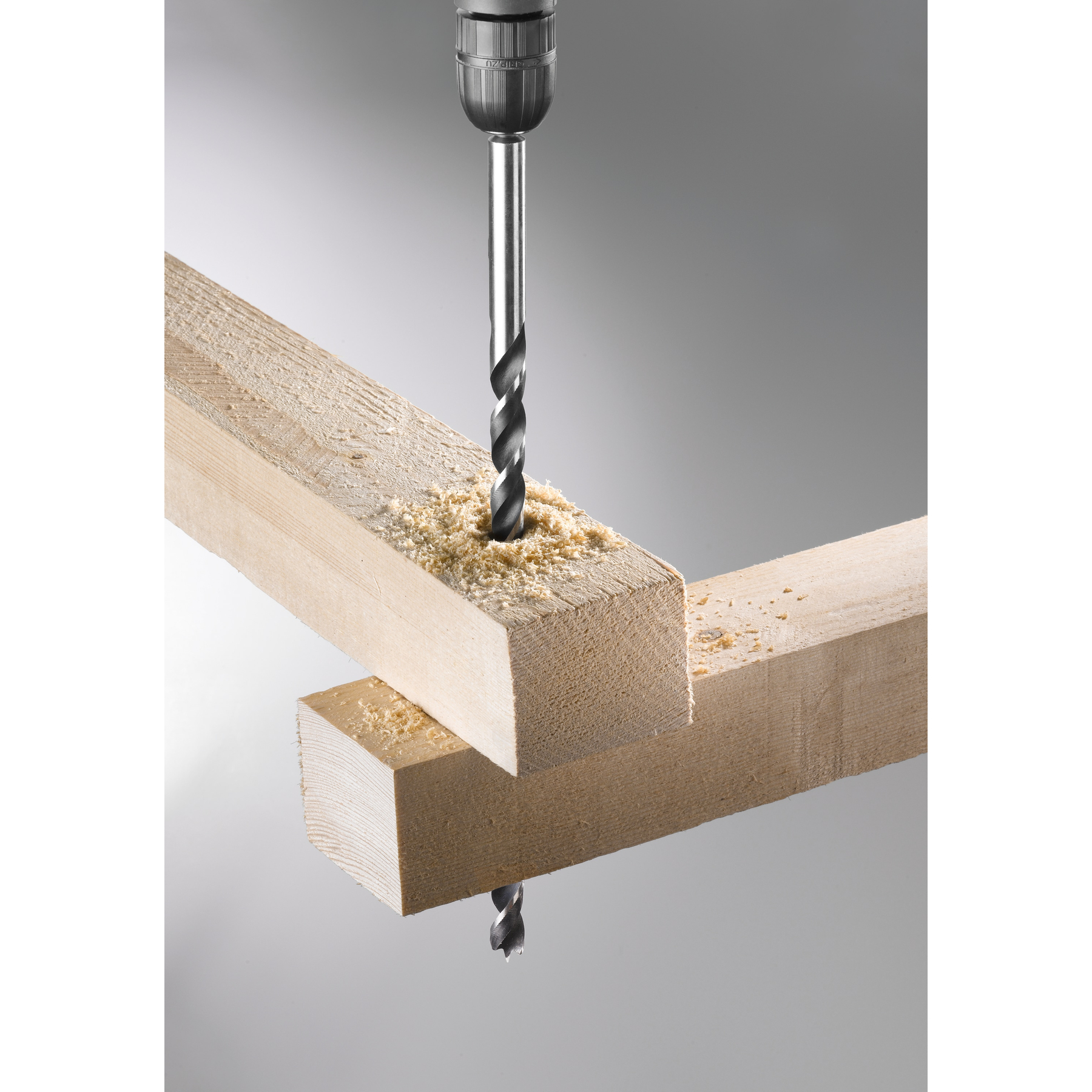 Ein Bohrer bohrt ein Loch in Holz, Holzspäne fliegen.