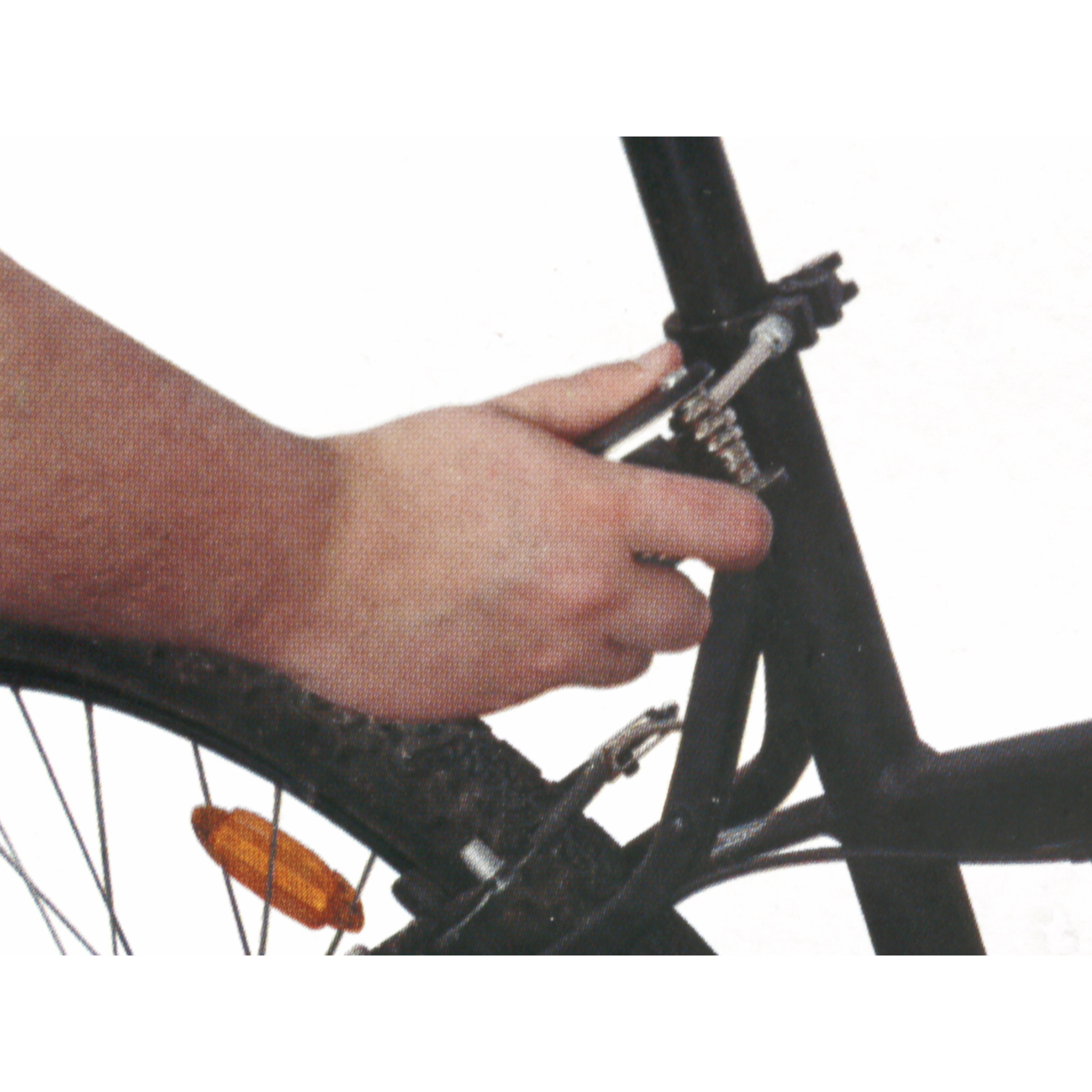 Eine Hand stellt eine Schraube am schwarzen Fahrradrahmen nahe dem Rad ein.