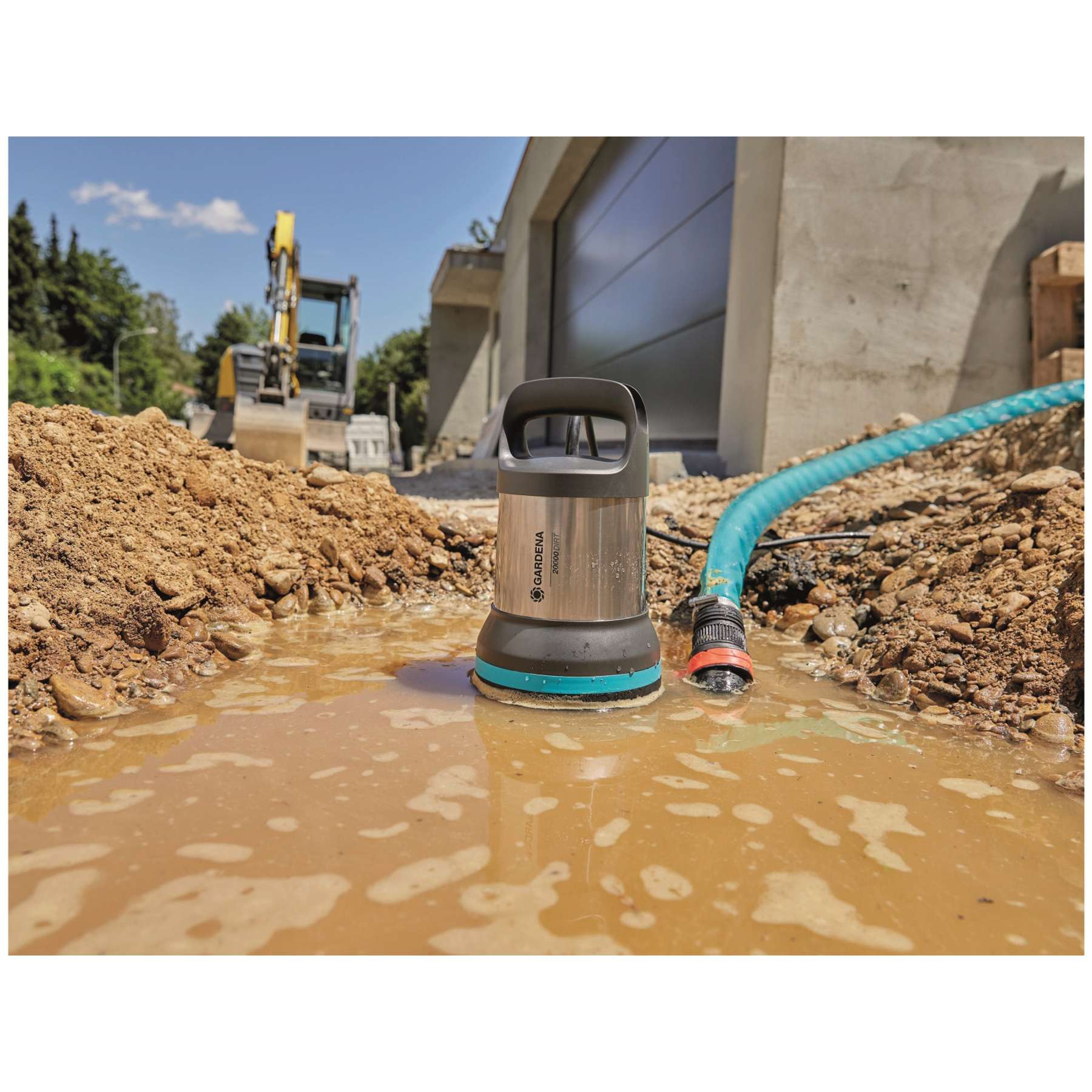 Tauchpumpe in schlammigem Wasser auf einer Baustelle mit Bagger im Hintergrund.