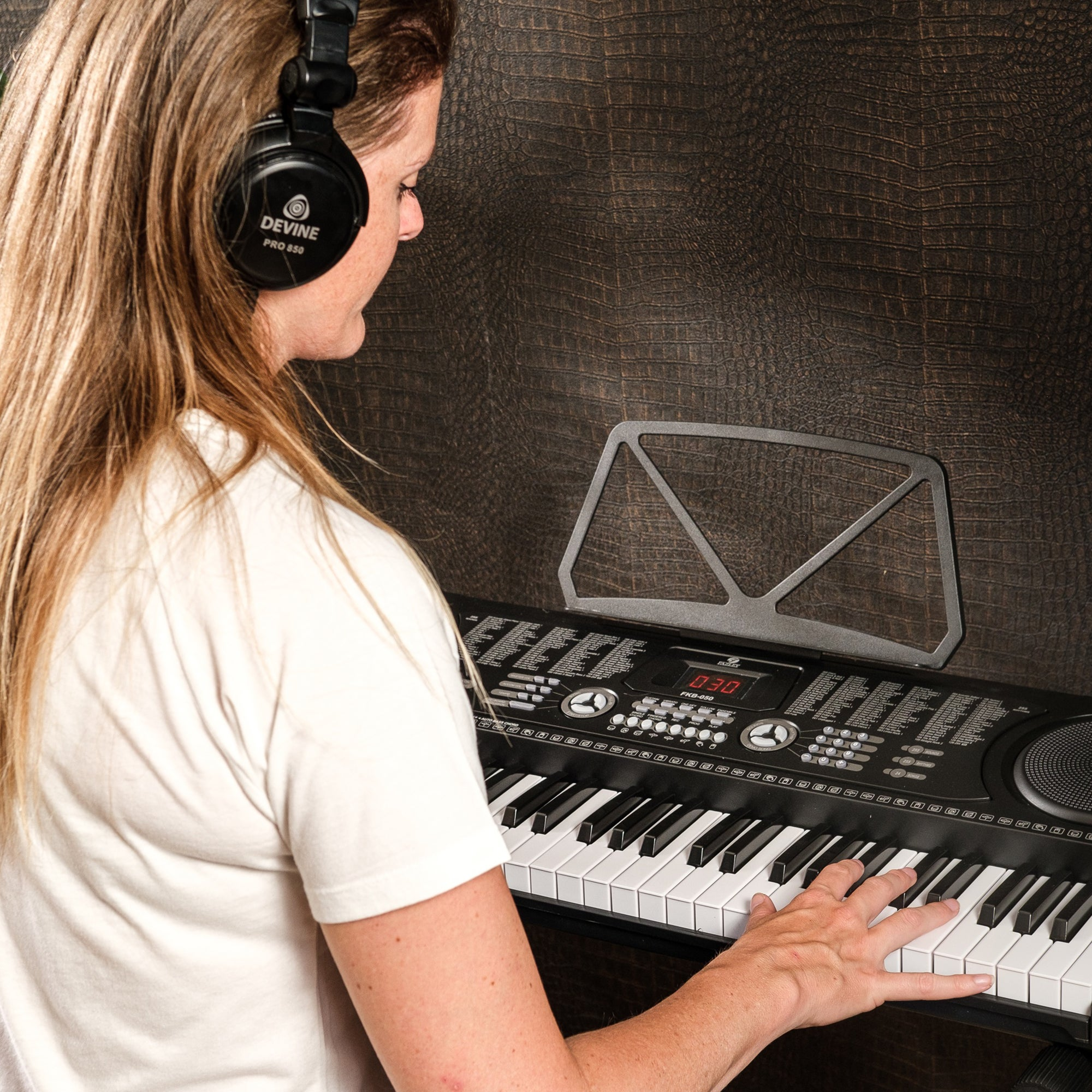Vrouw met koptelefoon speelt keyboard voor donkere achtergrond.