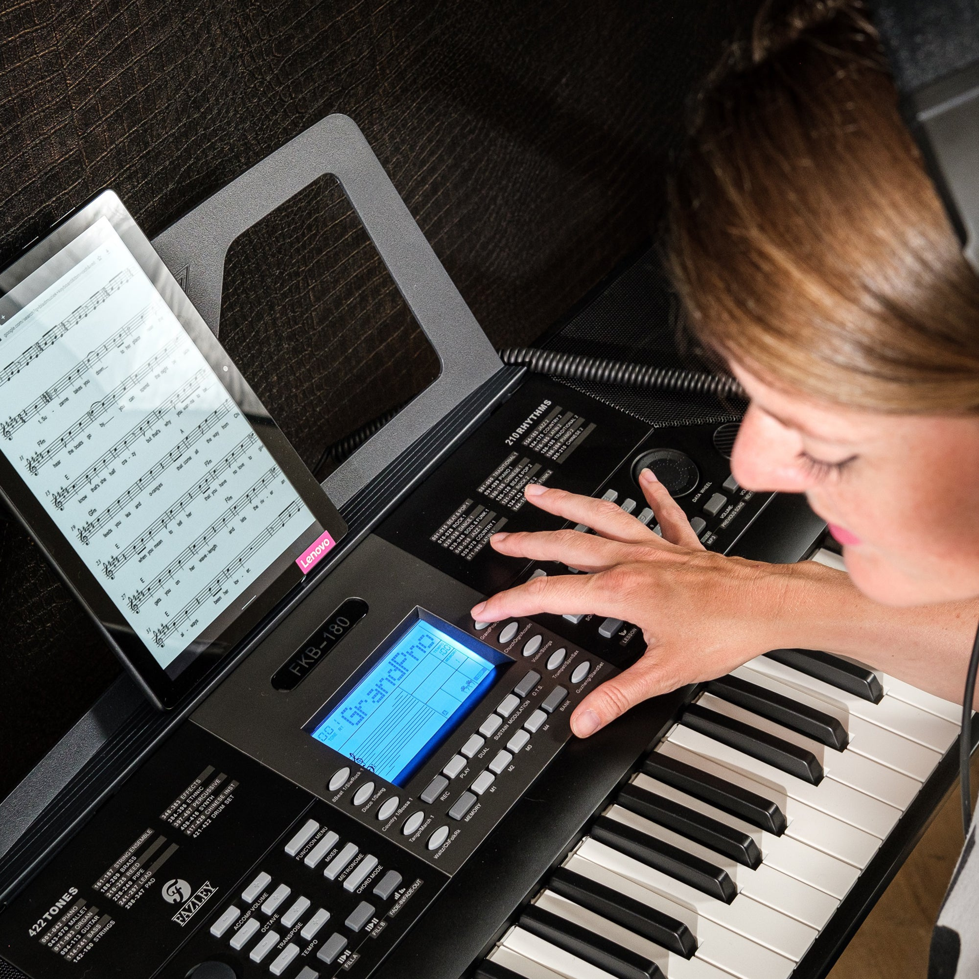 Een vrouw speelt keyboard met bladmuziek op een tablet.