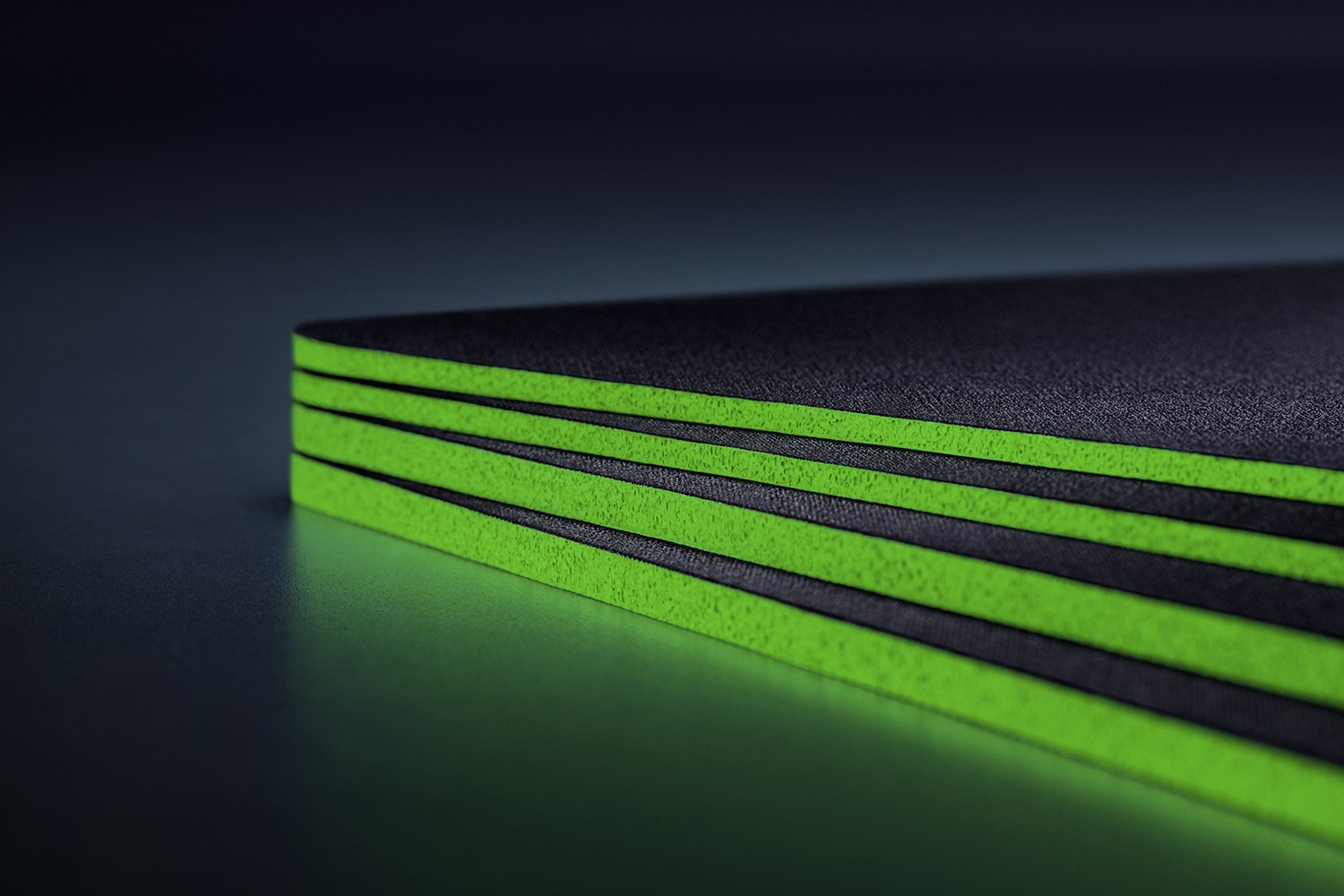 Una pila de alfombras negras con rayas verdes brillantes.