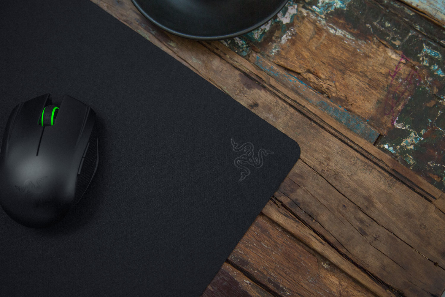 Mouse nero su tappetino nero con logo Razer su tavolo di legno.