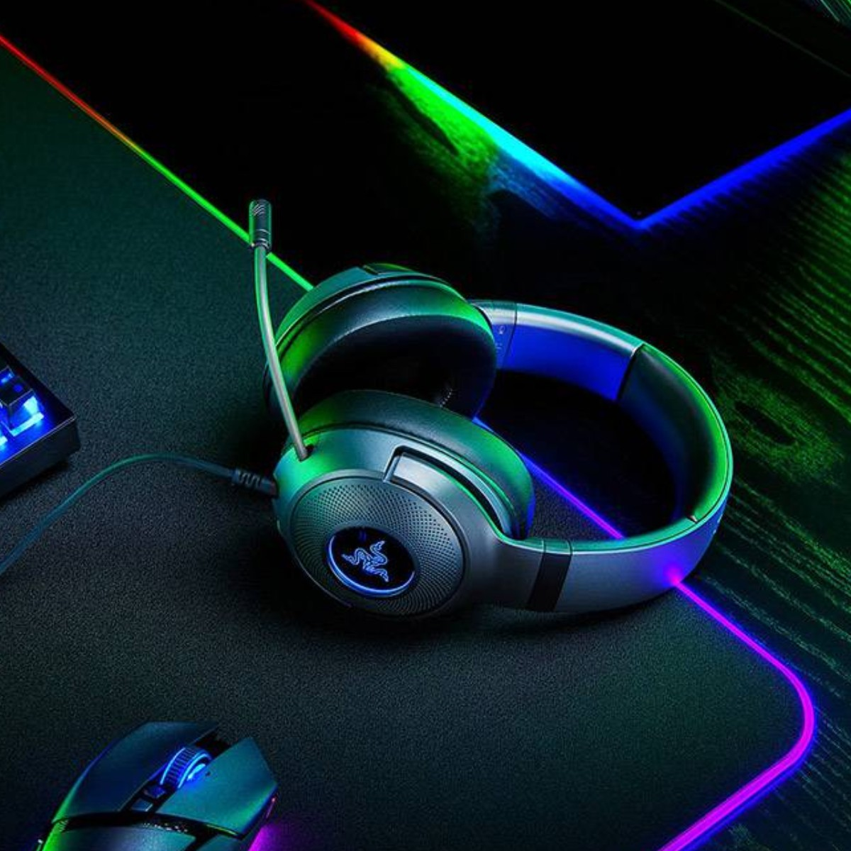 Ein Razer-Headset und eine Maus liegen auf einer schwarzen Matte mit RGB-Beleuchtung.