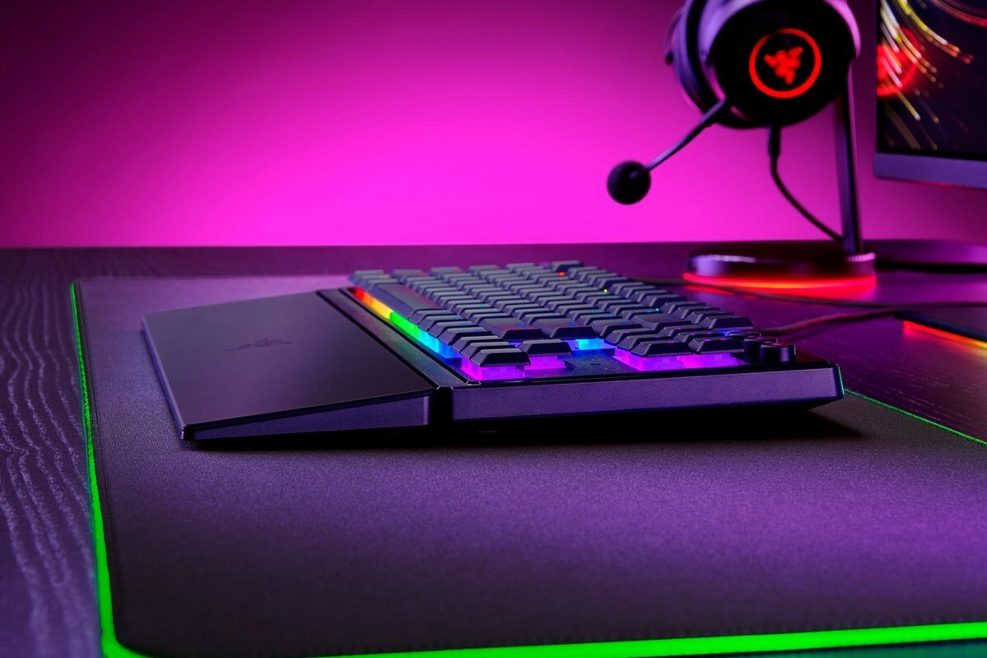 Una tastiera nera con illuminazione RGB poggia su un tappetino per mouse viola.