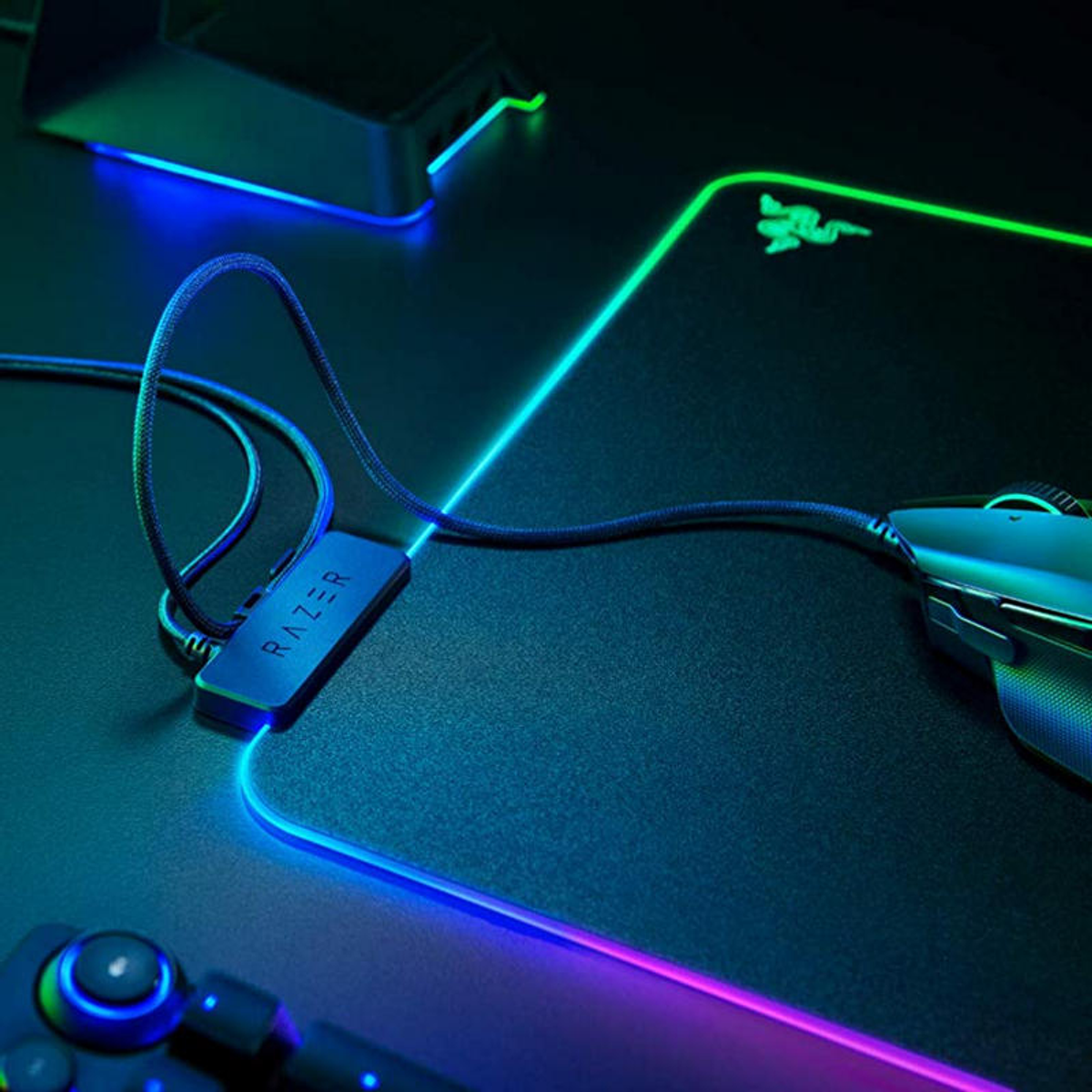 Mysz gamingowa Razer na podświetlanej podkładce z niebieskim i zielonym światłem.