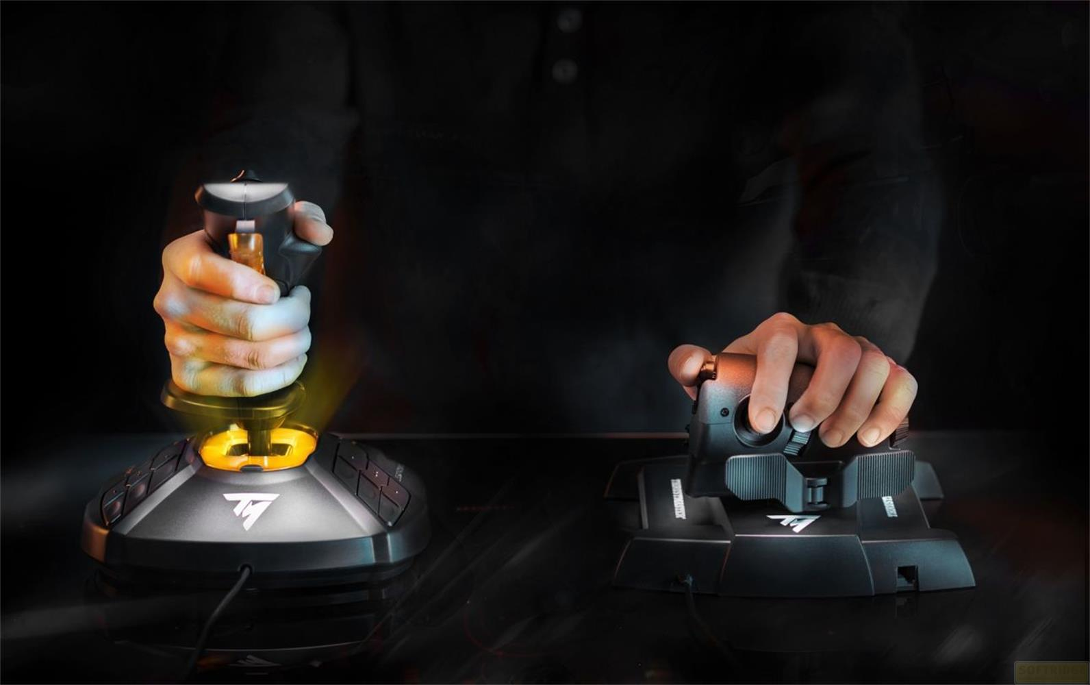 Ręce obsługujące joysticki. Jeden joystick świeci na żółto. Ciemne tło.