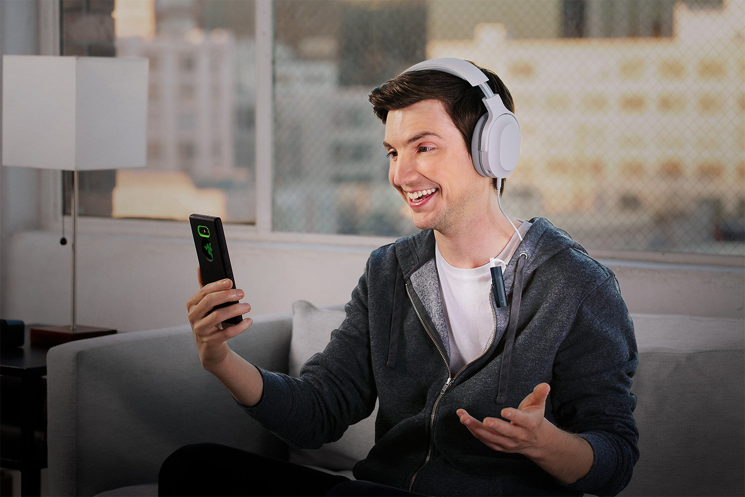 A man wearing headphones holds a smartphone and speaks.