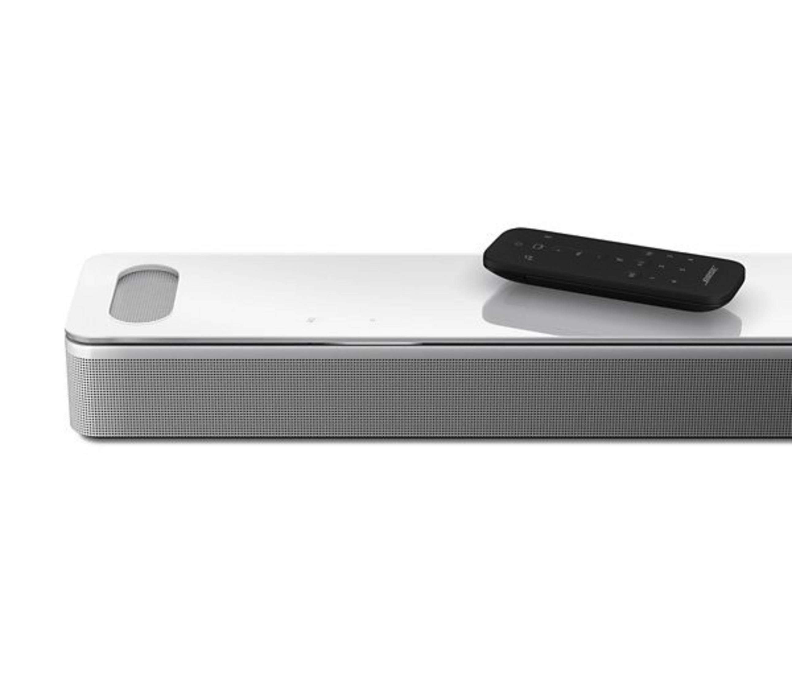 Weiße Soundbar mit Fernbedienung auf dem weißen Tisch.