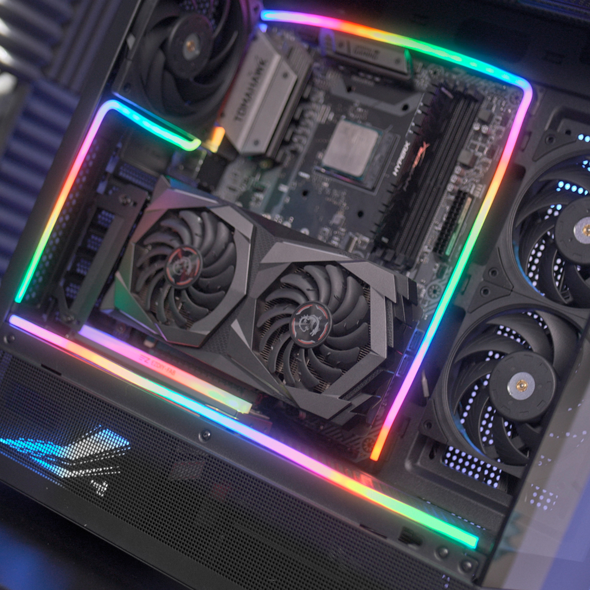Una caja de computadora con iluminación RGB, tarjeta gráfica, placa base y ventiladores.