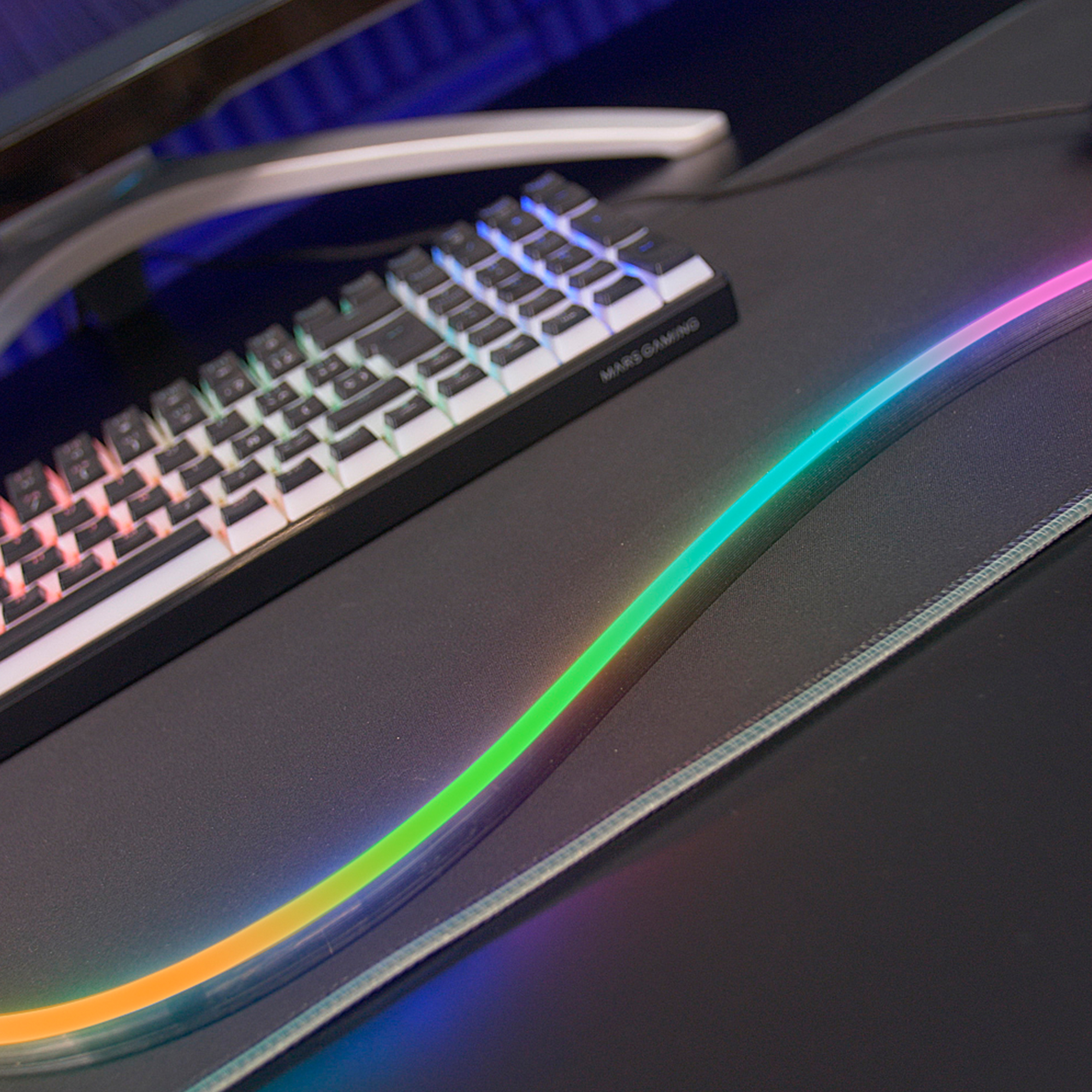 Un teclado blanco con iluminación RGB sobre un alfombrilla de ratón negra con RGB.