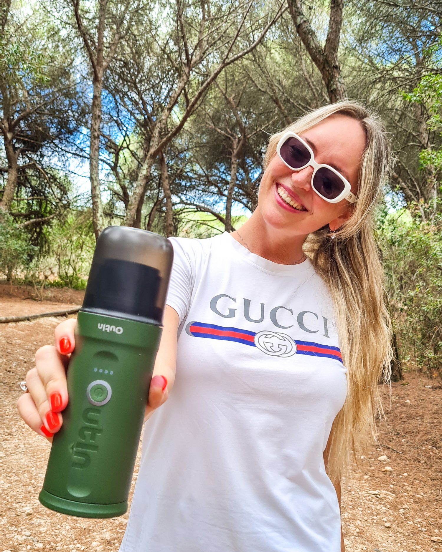 Een vrouw houdt een groene koffiemolen vast in een bos.