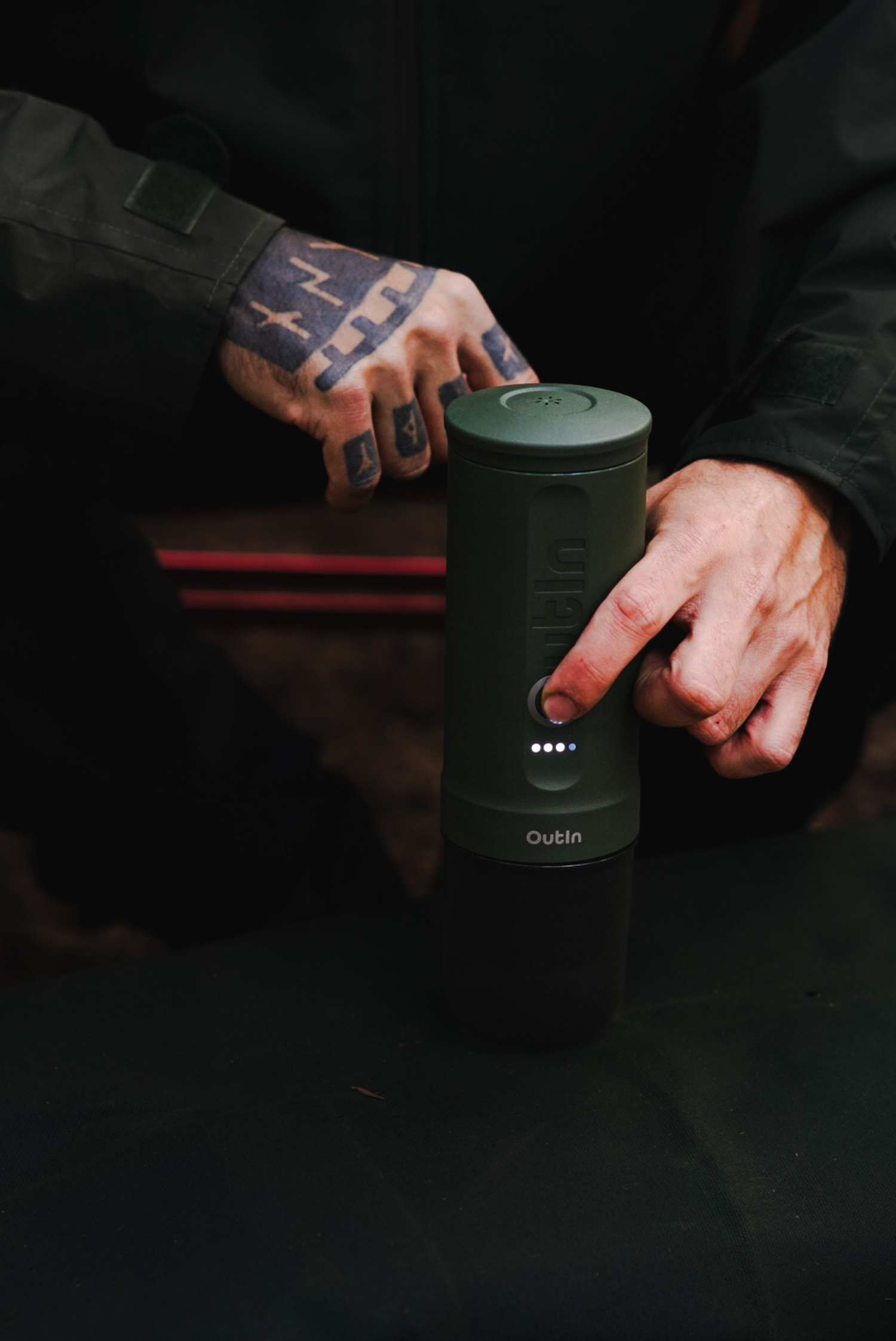 Groene koffiemachine bediend door persoon met tatoeages.