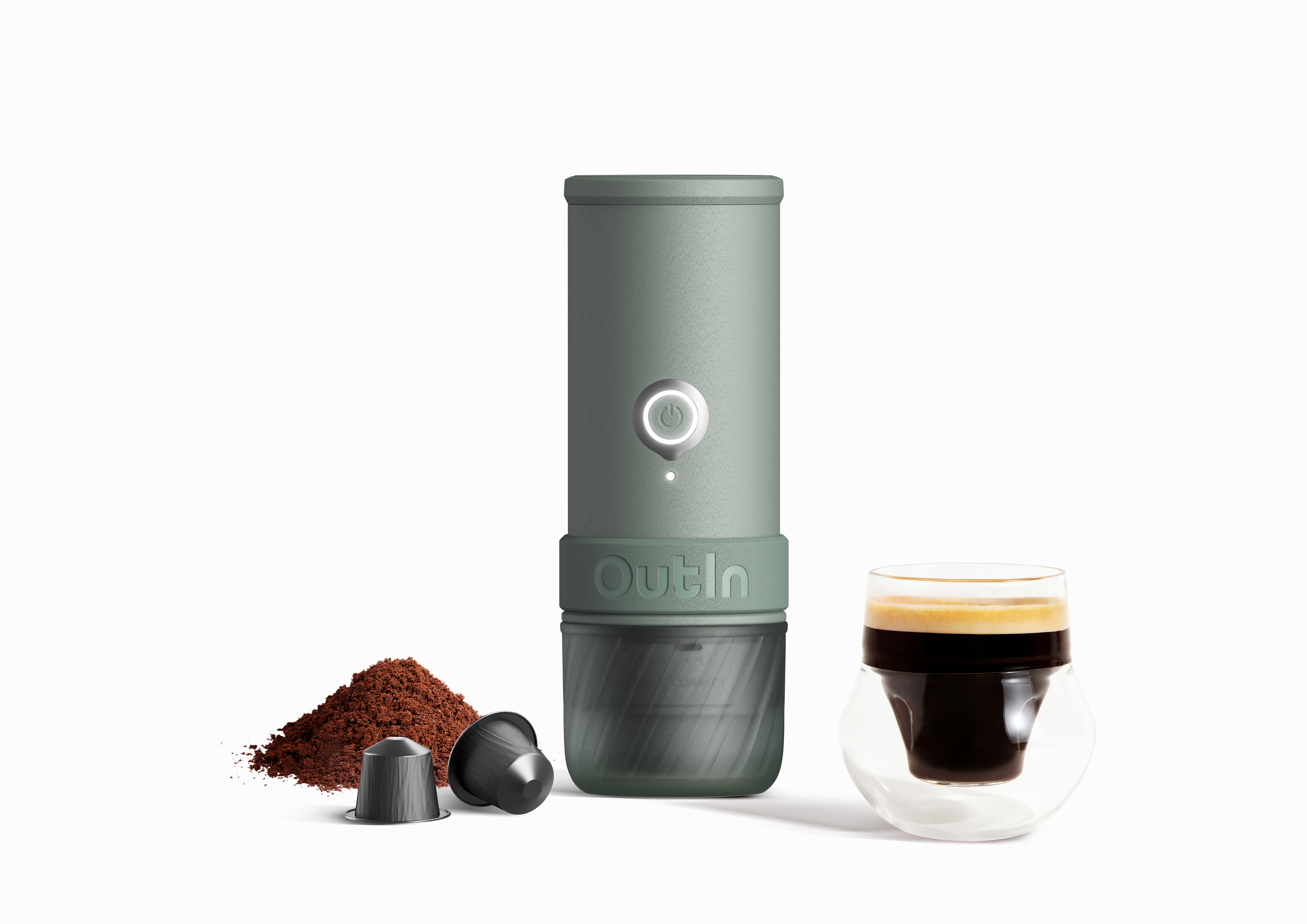 Grüne Kaffeemaschine mit Kaffeepulver, Kapseln und einem Glas Espresso.