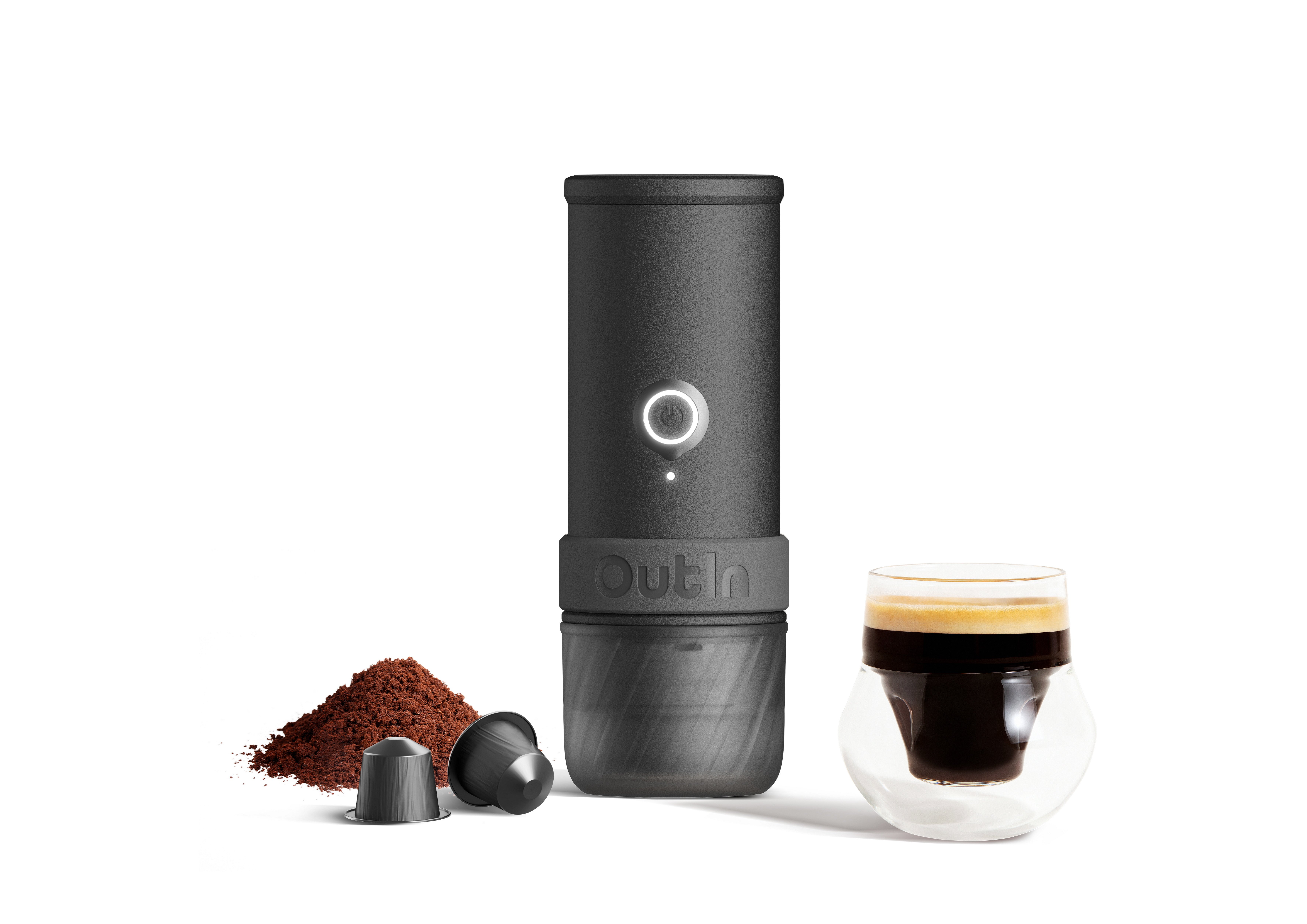 Schwarzer Kaffeebereiter mit Kaffeepulver, Kapseln und einem Glas Espresso.