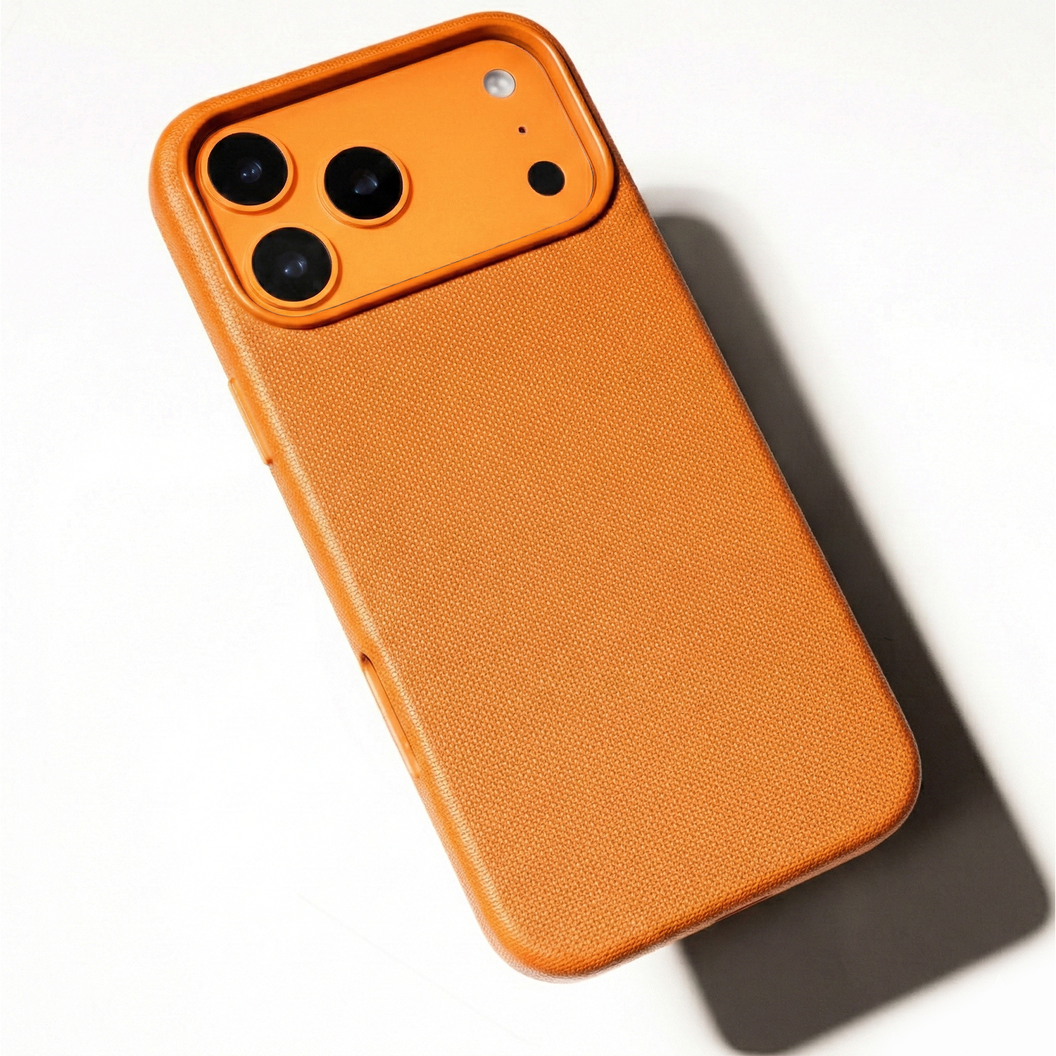Pomarańczowe etui na telefon z potrójnym aparatem, na białym tle.