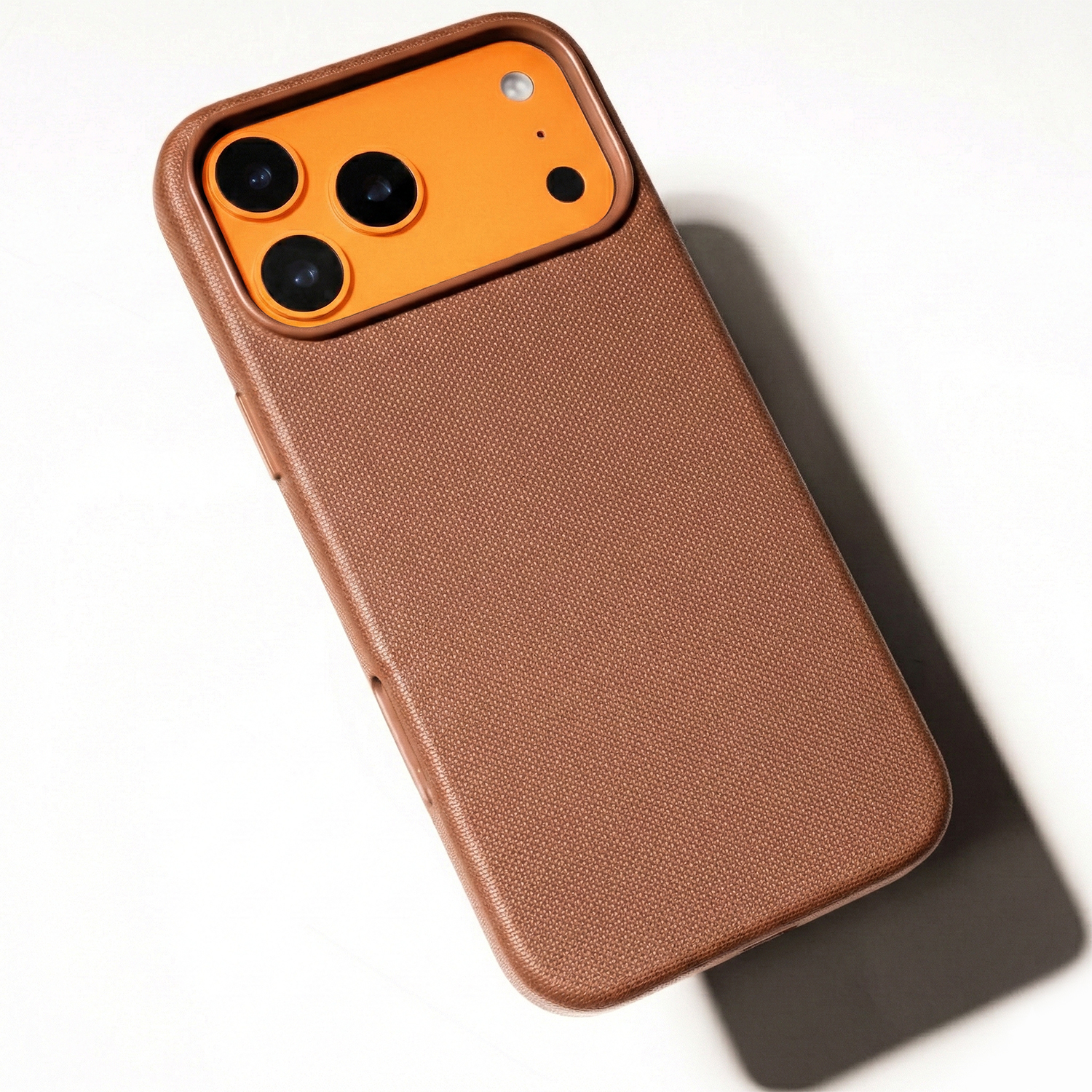 Brązowe etui na telefon z pomarańczowym modułem aparatu i trzema obiektywami.
