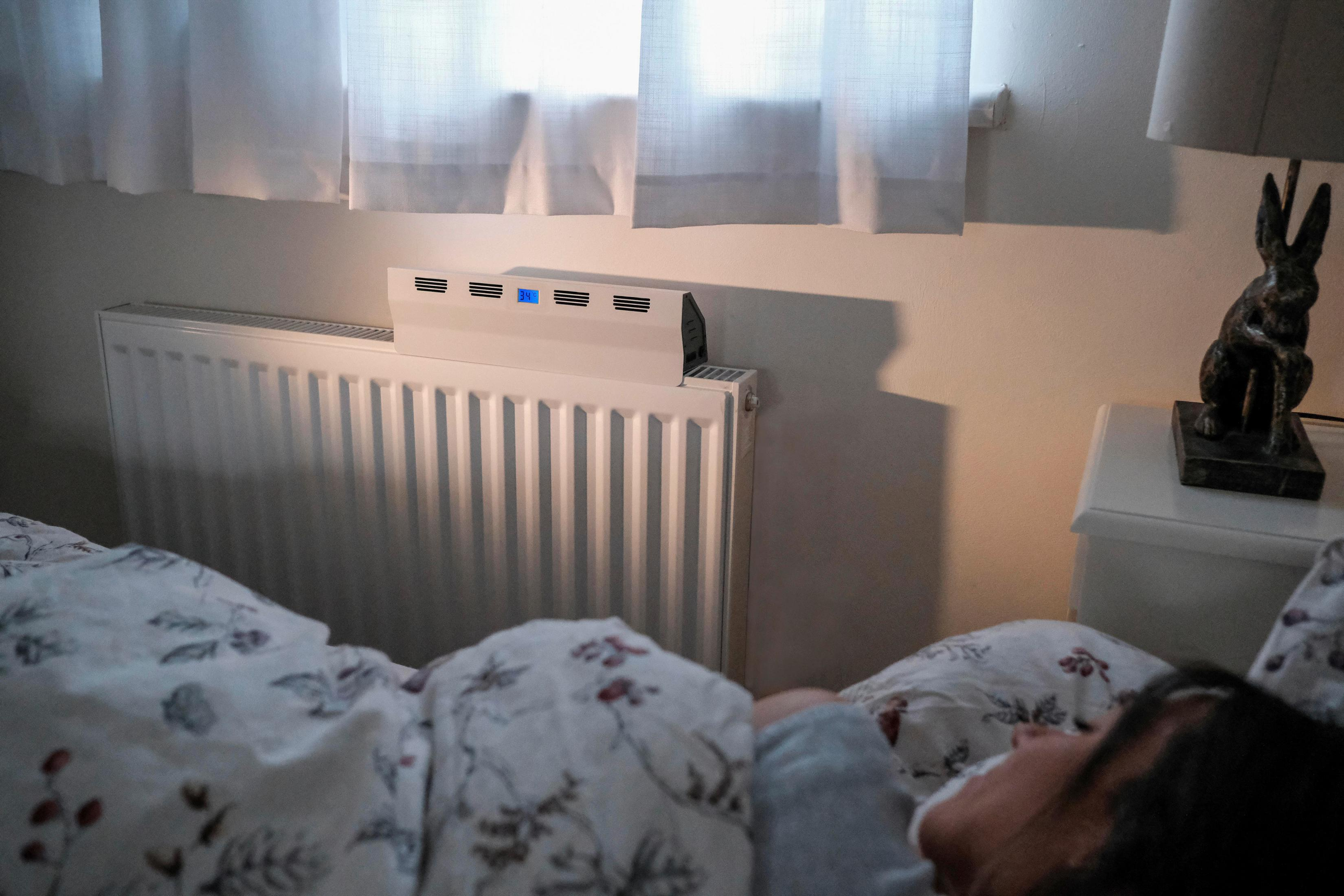 Un letto con coperte a fantasia e un termosifone con display digitale.