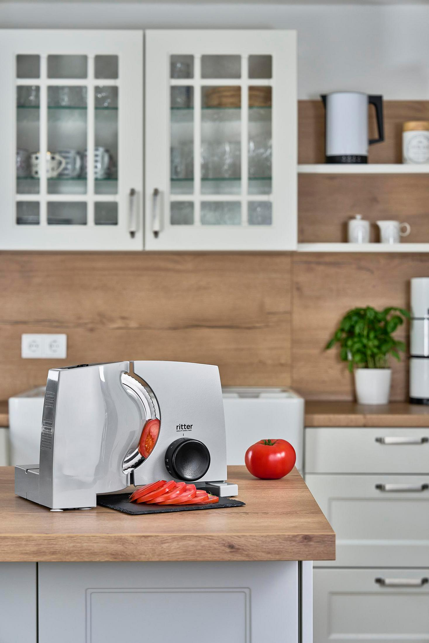 Srebrna krajalnica z plasterkami pomidora stoi na drewnianym blacie.