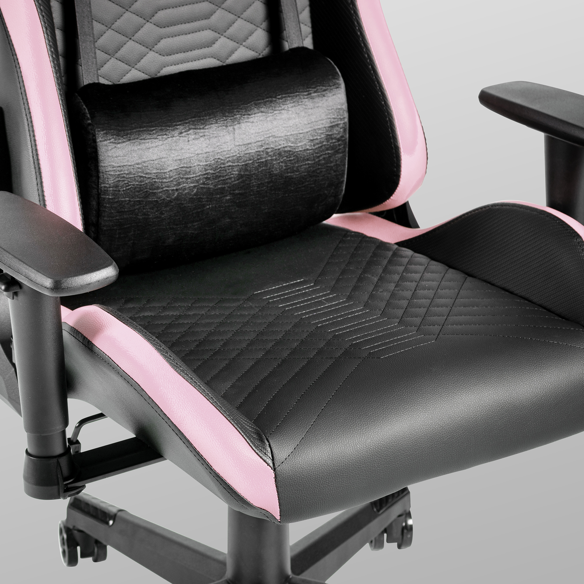Silla gamer negra con detalles rosas, cojín cervical y pespuntes de diamante.