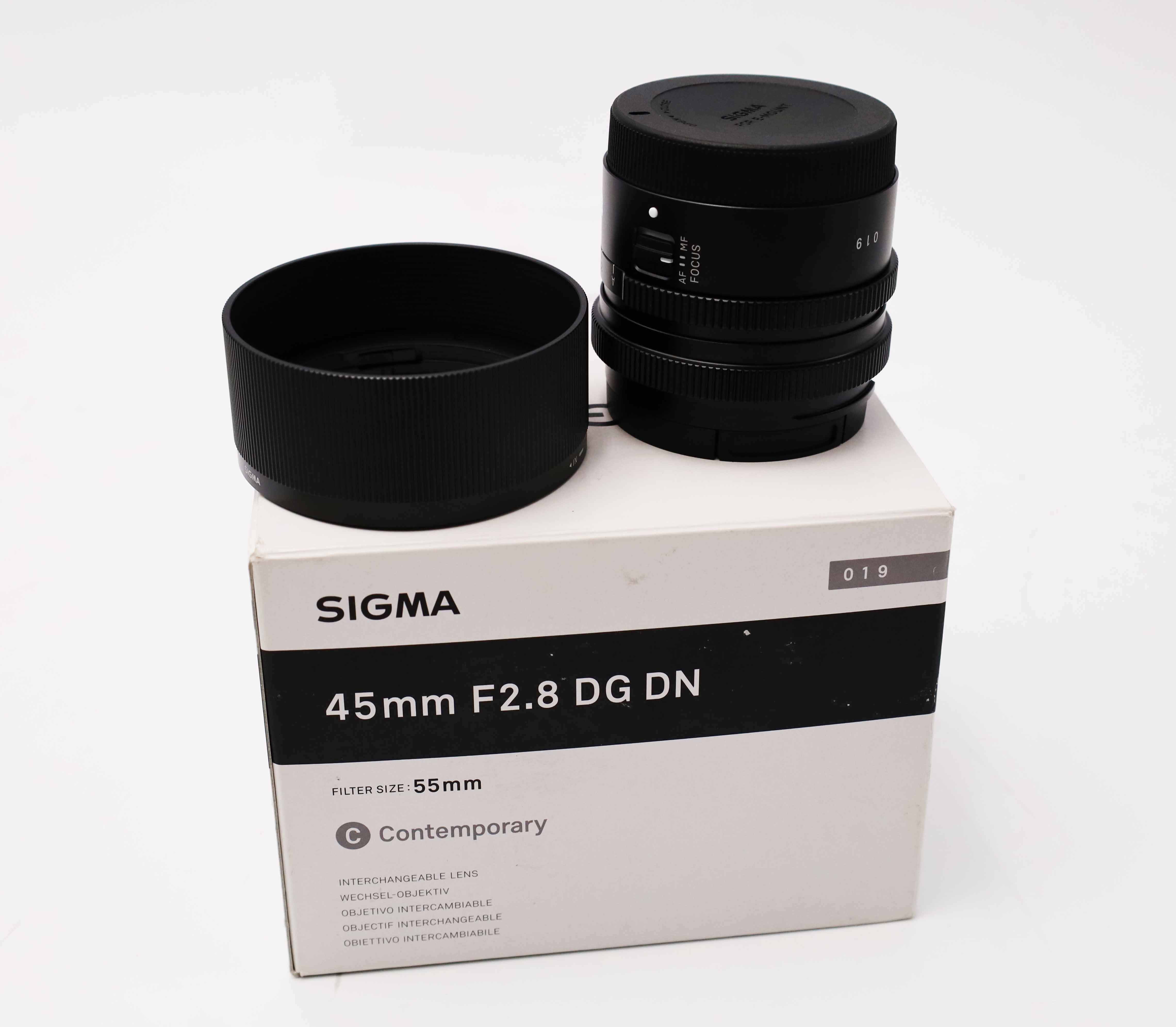 Obiektyw Sigma 45mm F2.8 DG DN z osłoną przeciwsłoneczną i pudełkiem.
