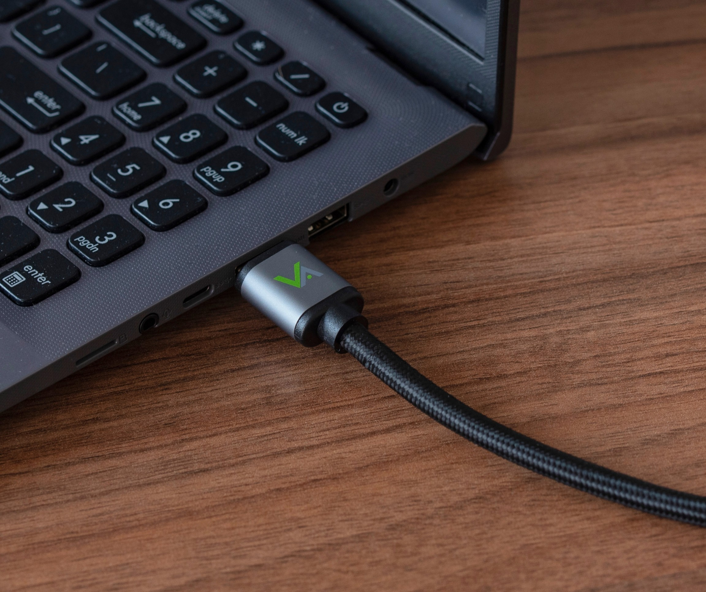 Czarny kabel USB z zielonym logo podłączony do laptopa.