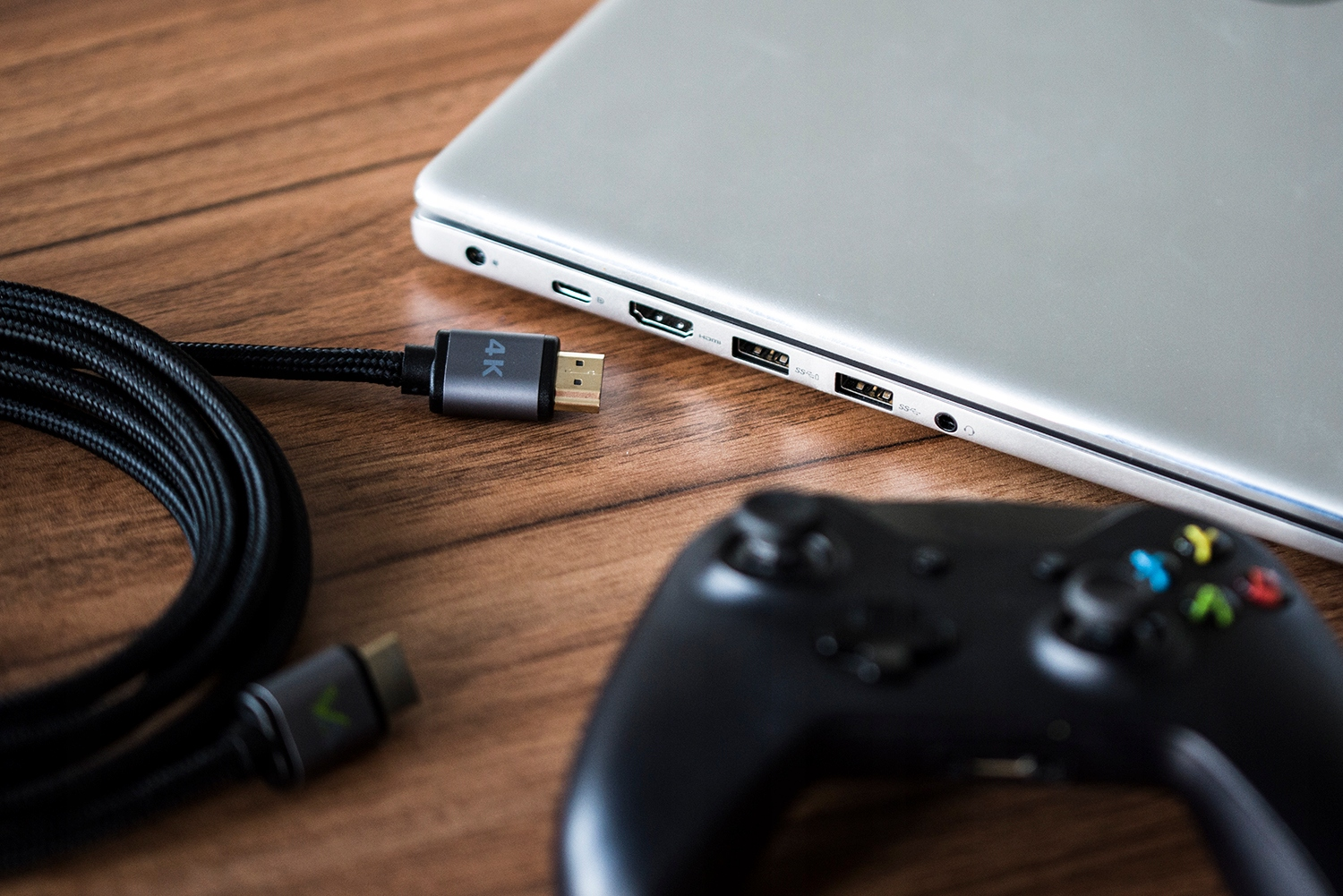 Kabel HDMI z oznaczeniem 4K leży obok laptopa i kontrolera.