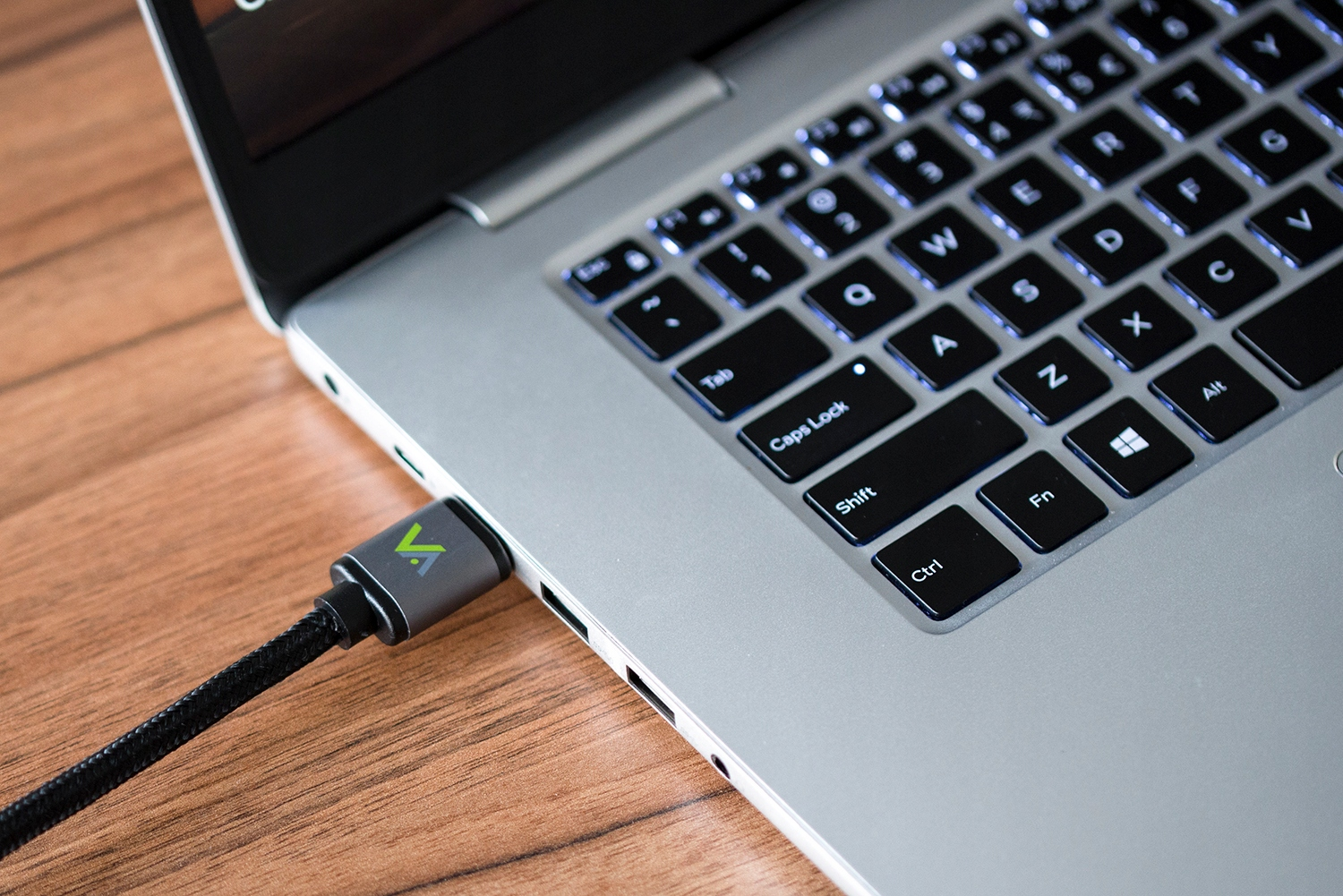 Szary kabel USB z zielonym logo jest podłączony do laptopa.