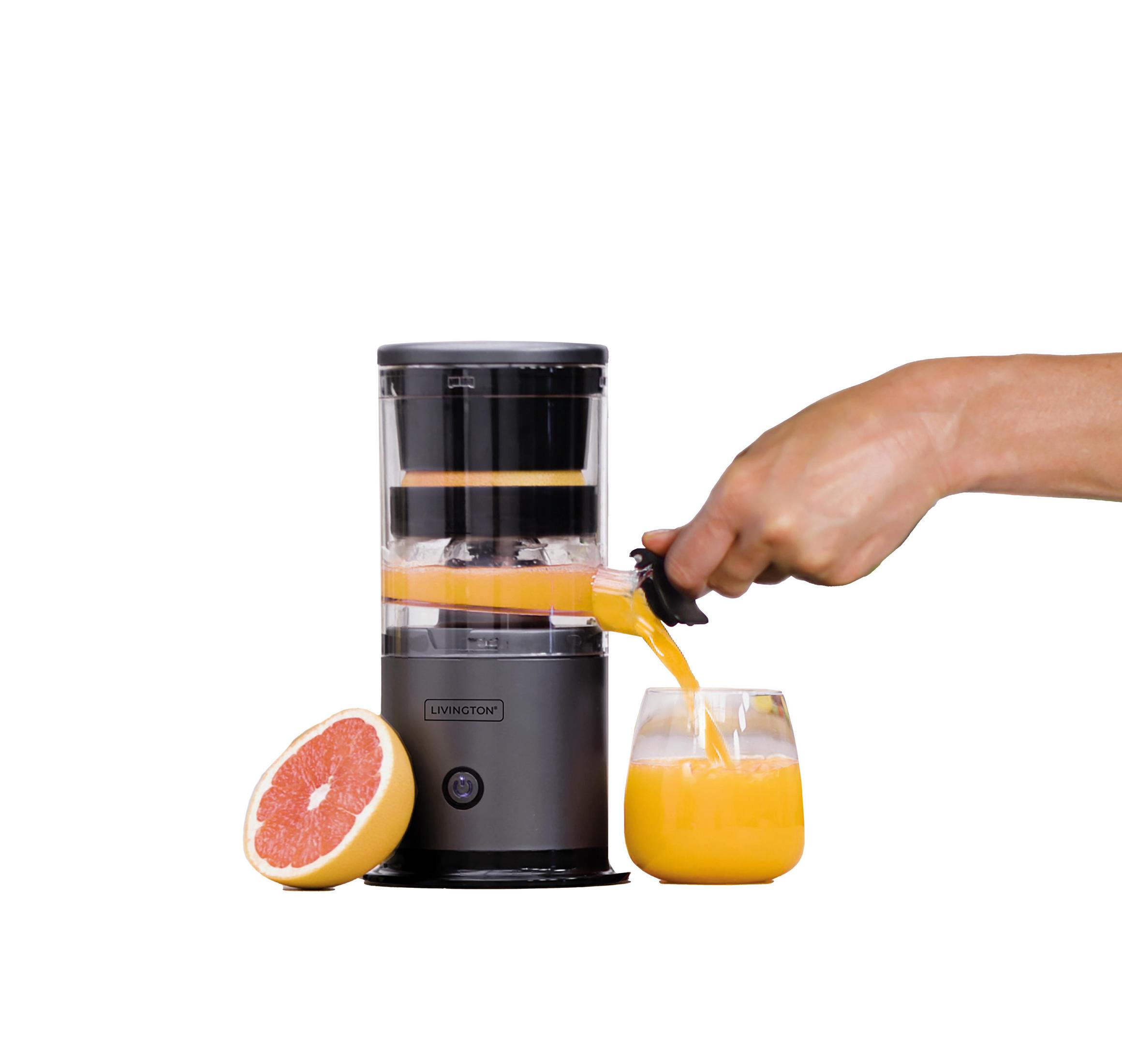 Eine Hand gießt Orangensaft aus einem Entsafter in ein Glas. Grapefruit daneben.