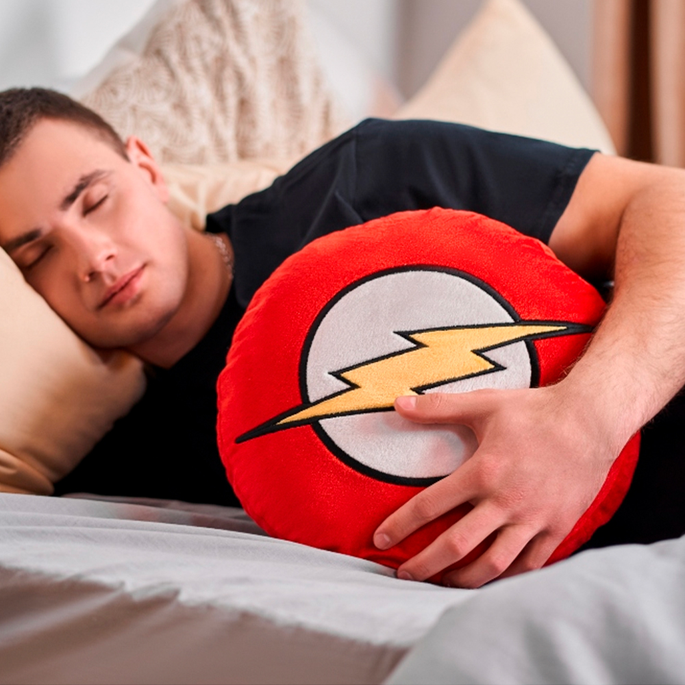 Un uomo dorme su un letto tenendo un cuscino rosso con il logo del fulmine di Flash.