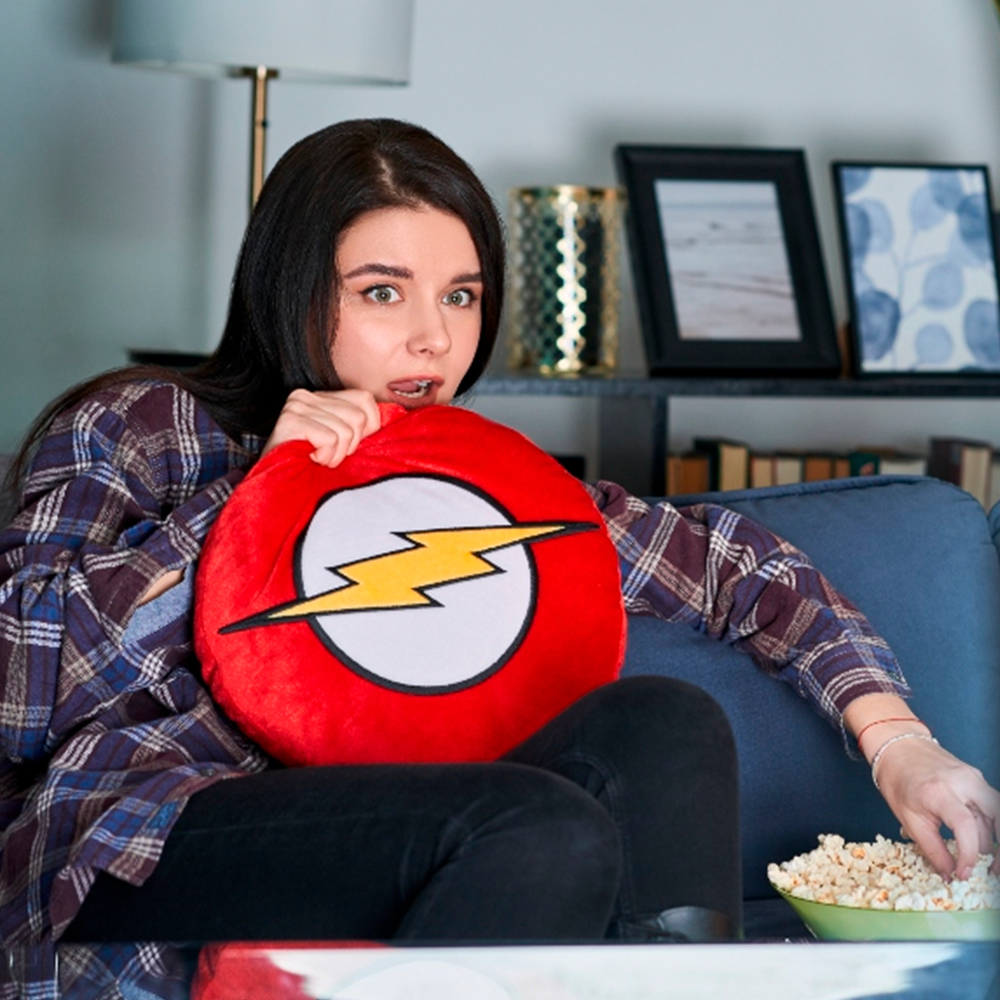 Una donna seduta sul divano tiene un cuscino con il logo di Flash e mangia popcorn.