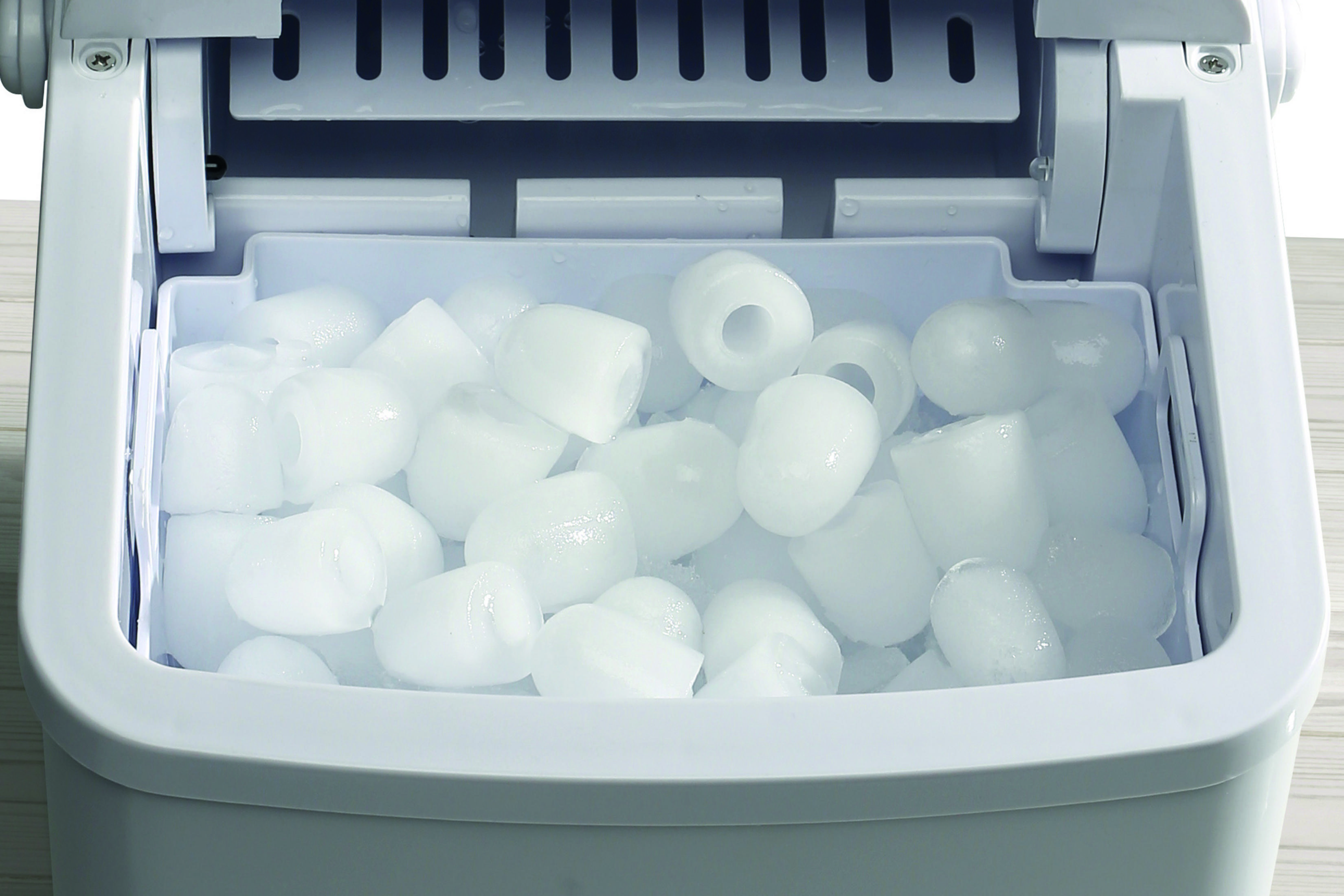 Biała kostkarka do lodu z wieloma kostkami lodu w pojemniku.