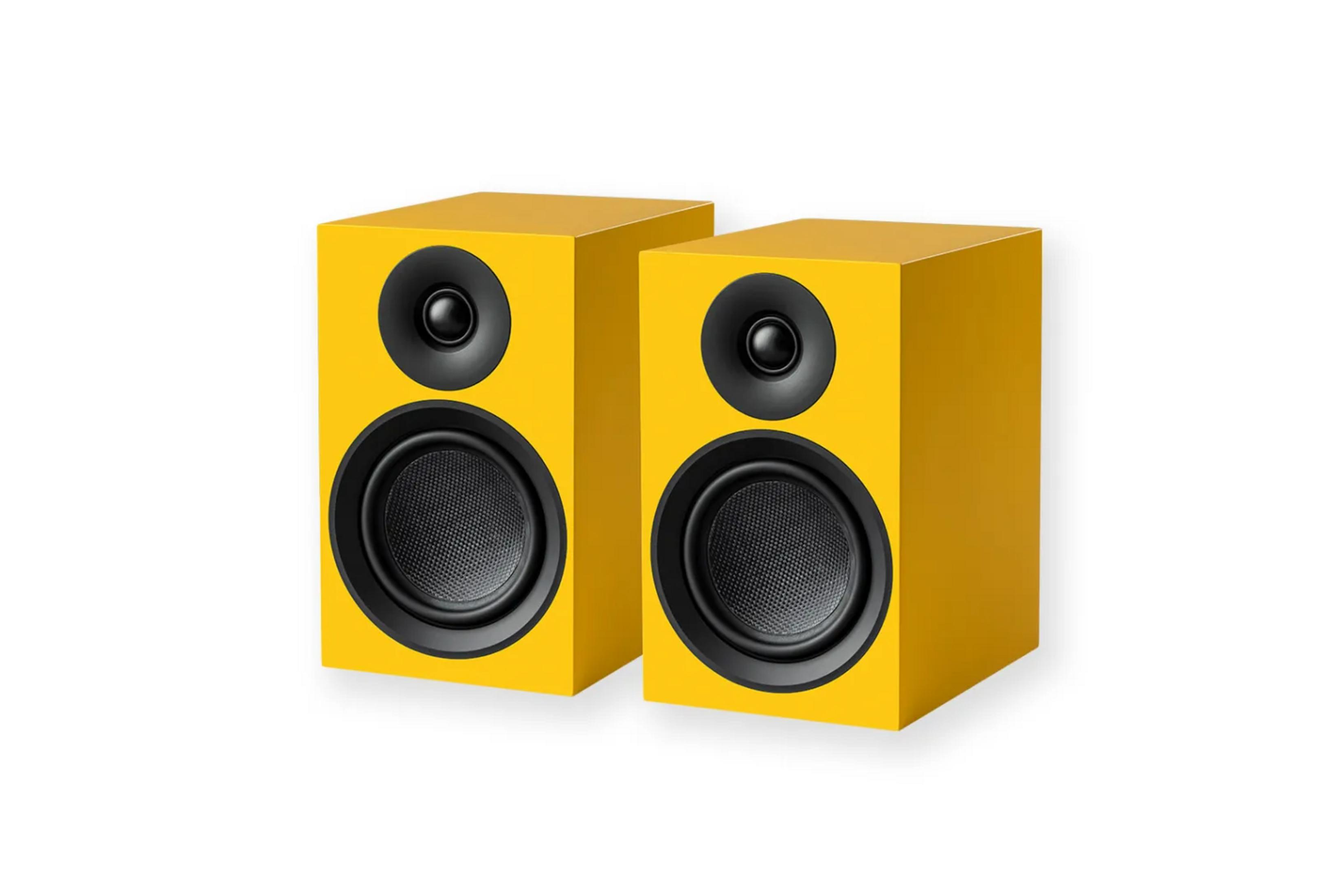 Dwa żółte głośniki z czarnymi membranami stoją obok siebie.