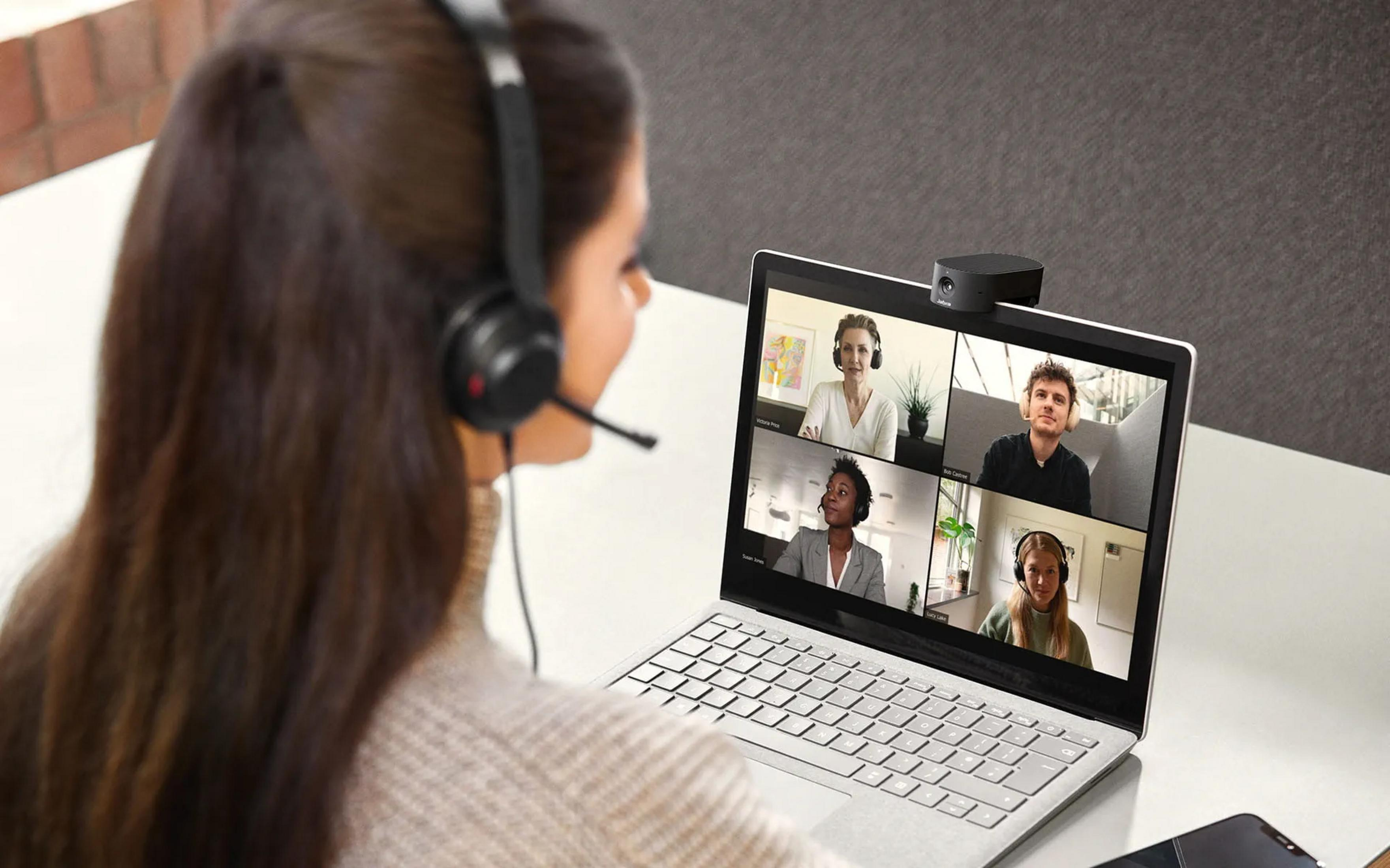 Donna con cuffie in videoconferenza con quattro persone.