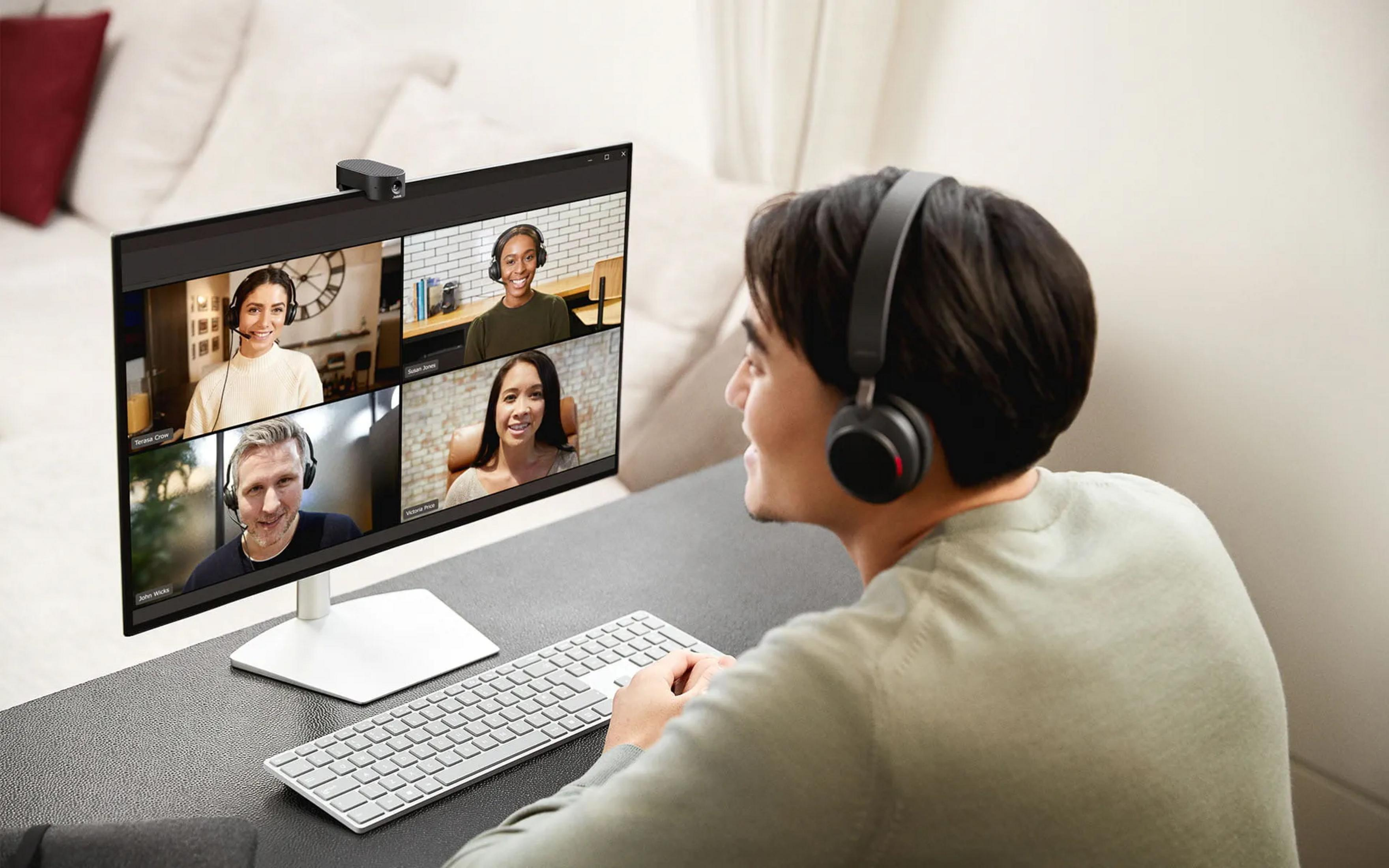 Persona con cuffie durante una riunione online con quattro persone sullo schermo.