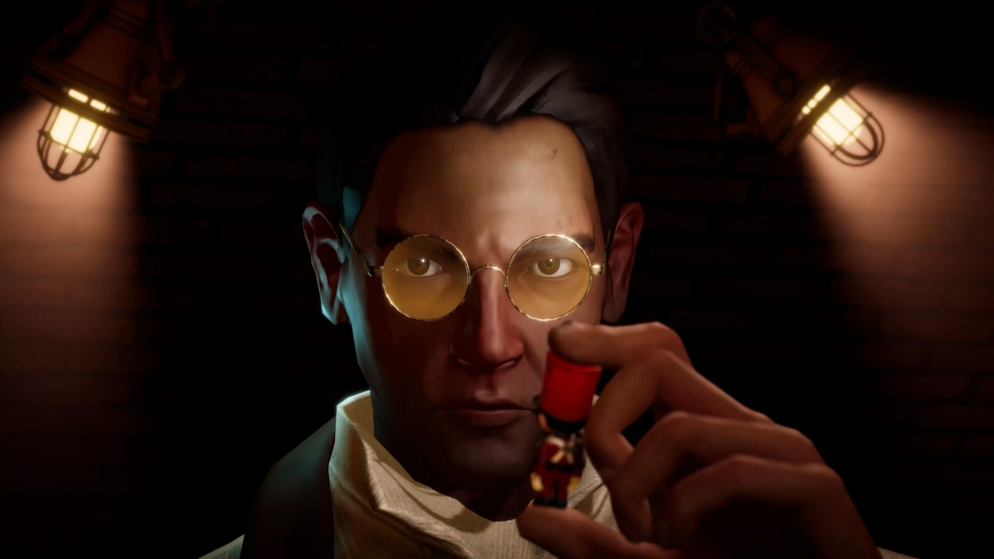 Mann mit Brille hält winzige rote Figur unter zwei Lampen.